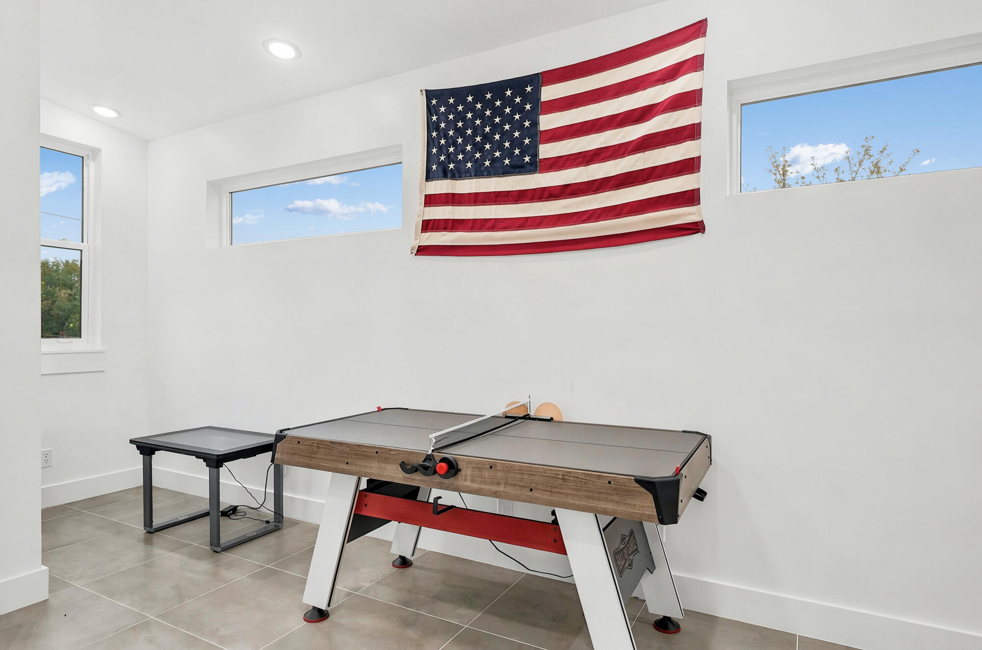 Game room with a table tennis table, net, paddles, and an American flag.