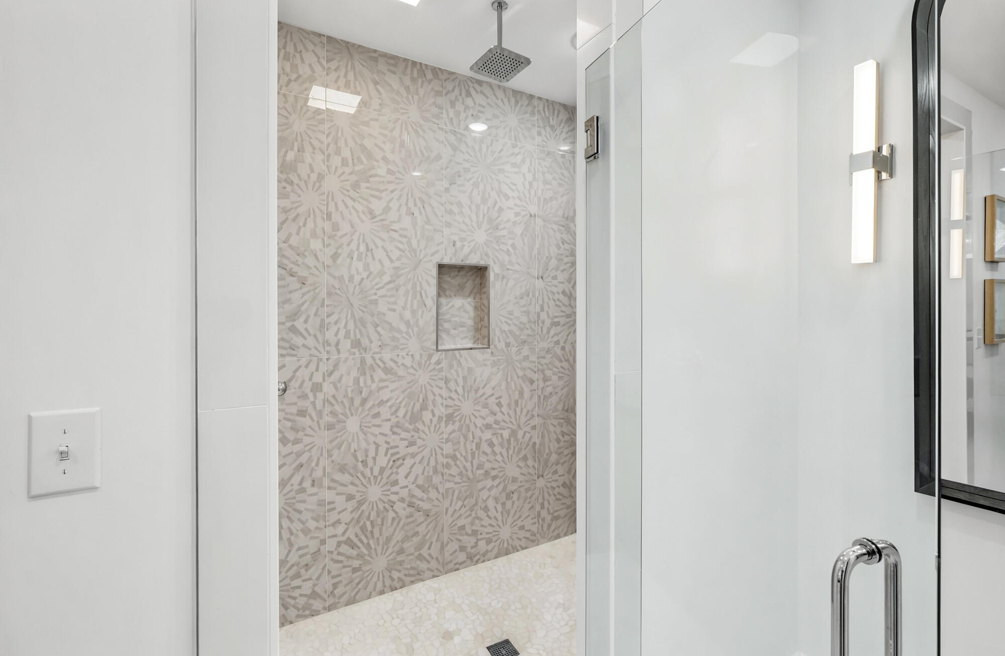 Walk-in shower with geometric patterned tile, a built-in niche, and glass enclosure.