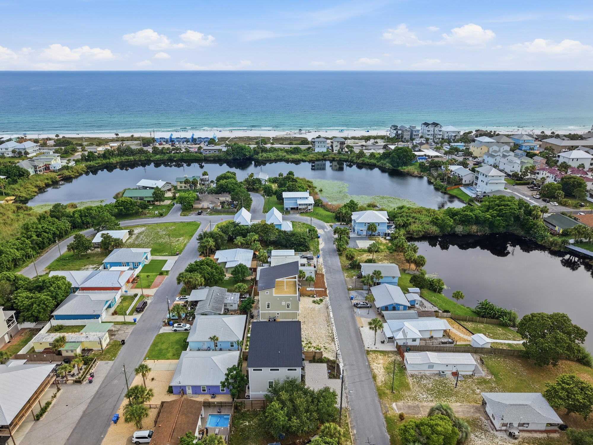 Aerial view of coastal homes between a lagoon and the Gulf beach.