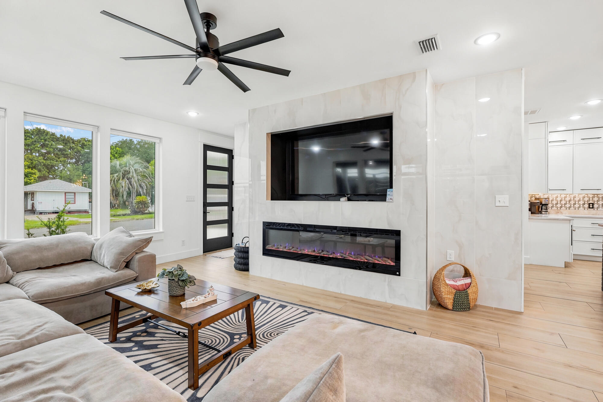 Living room with a marble-look media wall, electric fireplace, and large windows.