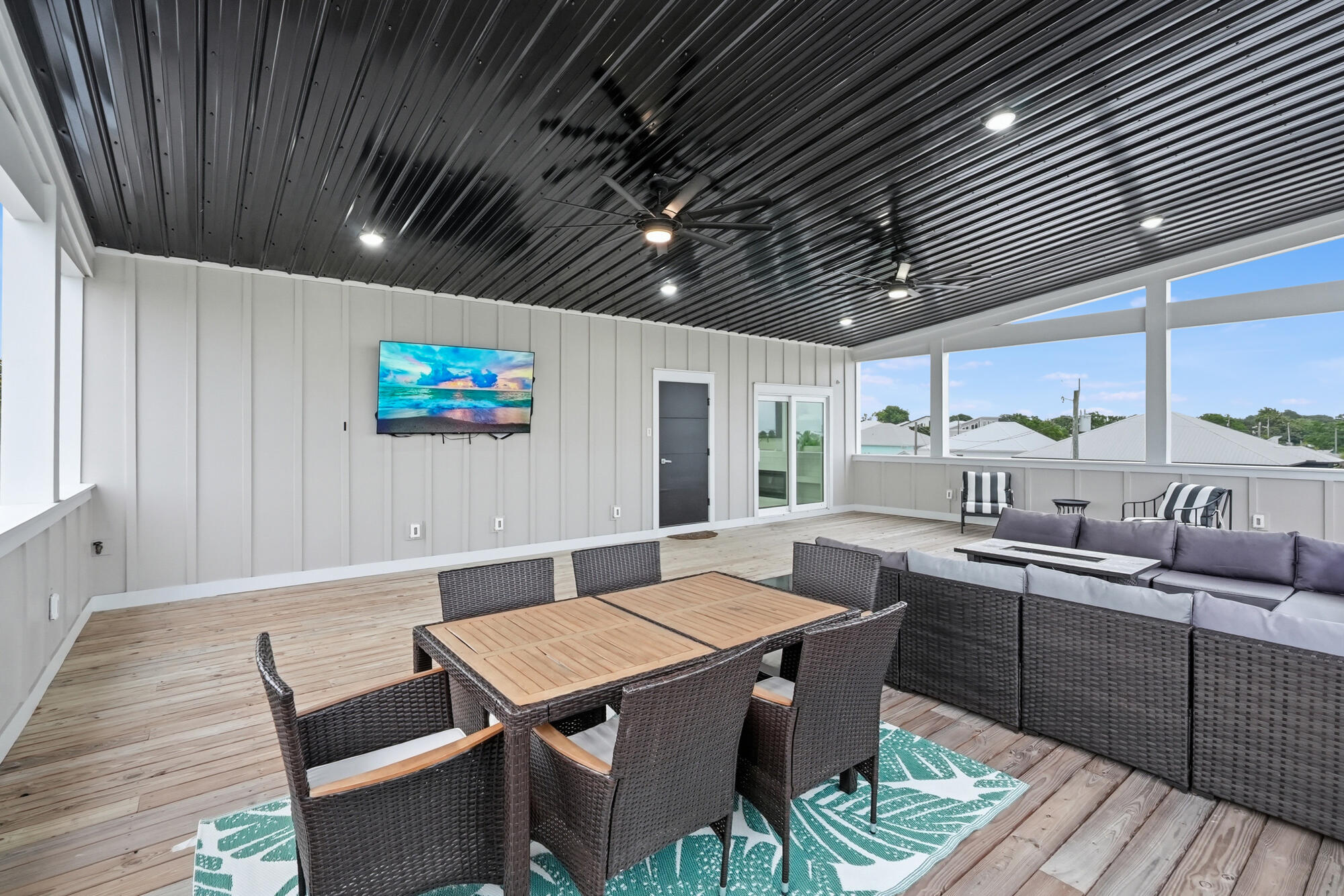 Covered patio with wicker dining and lounge furniture, wood decking, and a black metal ceiling.