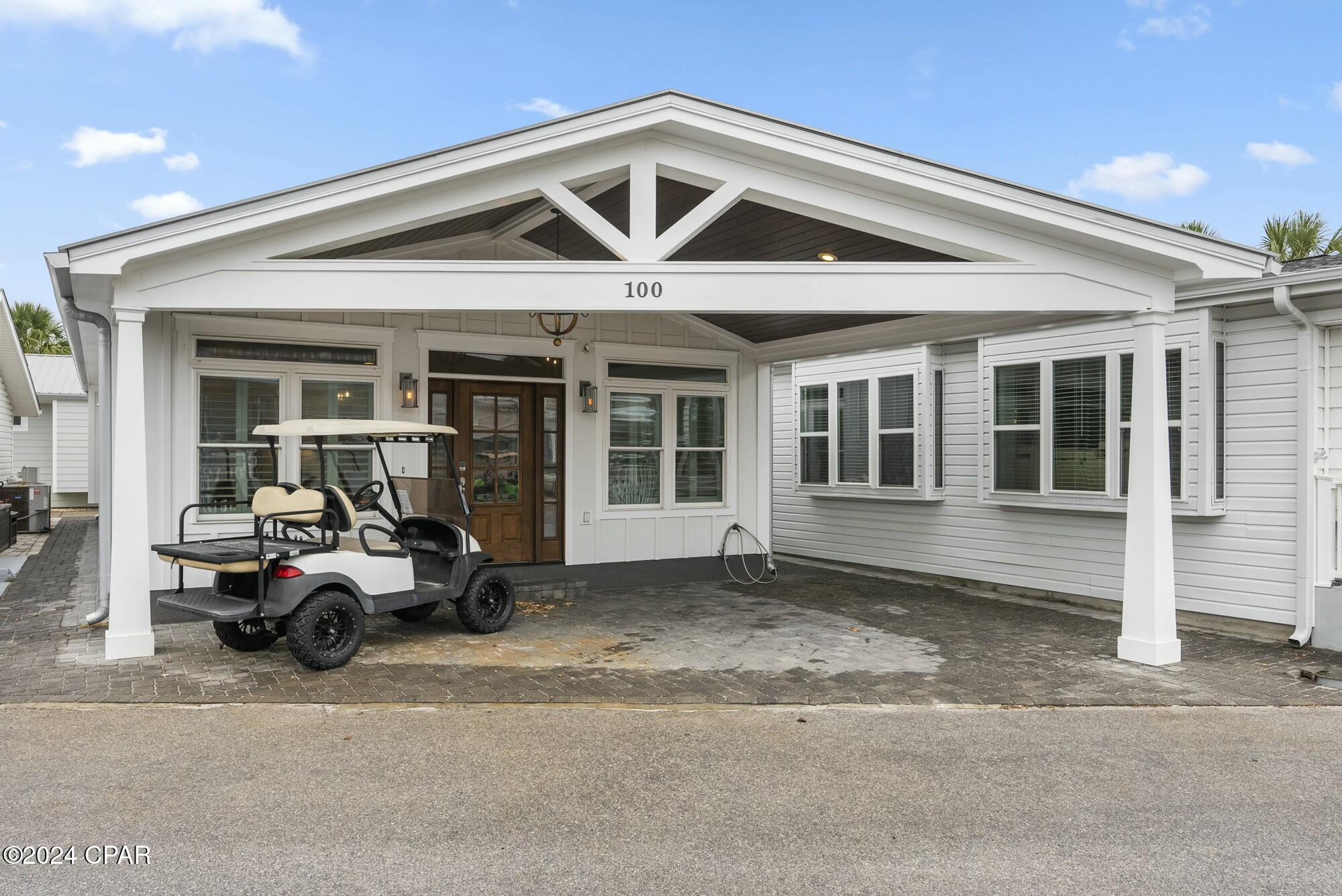 White home with a broad covered entrance and a golf cart parked in the driveway.