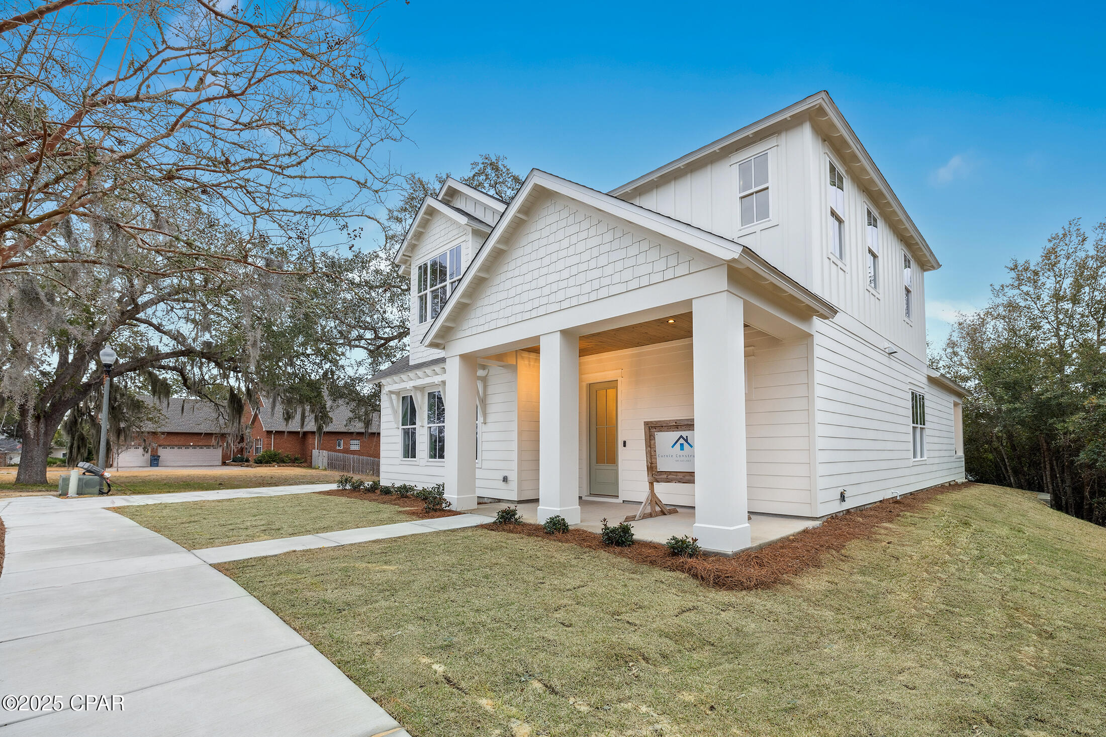 White two-story house with a covered porch, front lawn, and concrete walkway.