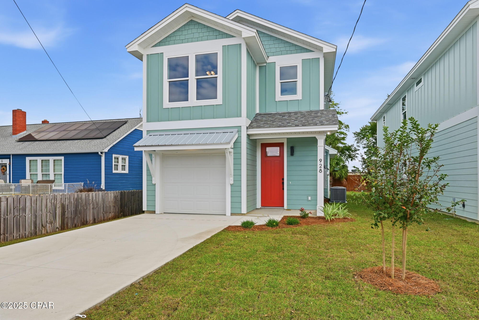 Mint-green two-story house with white trim, red front door, attached garage, and front lawn.