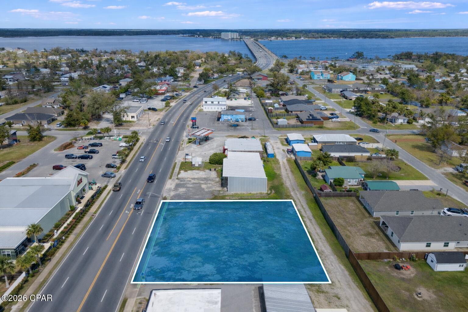 Aerial view of an outlined vacant parcel beside a road, with the bay and bridge in the distance.