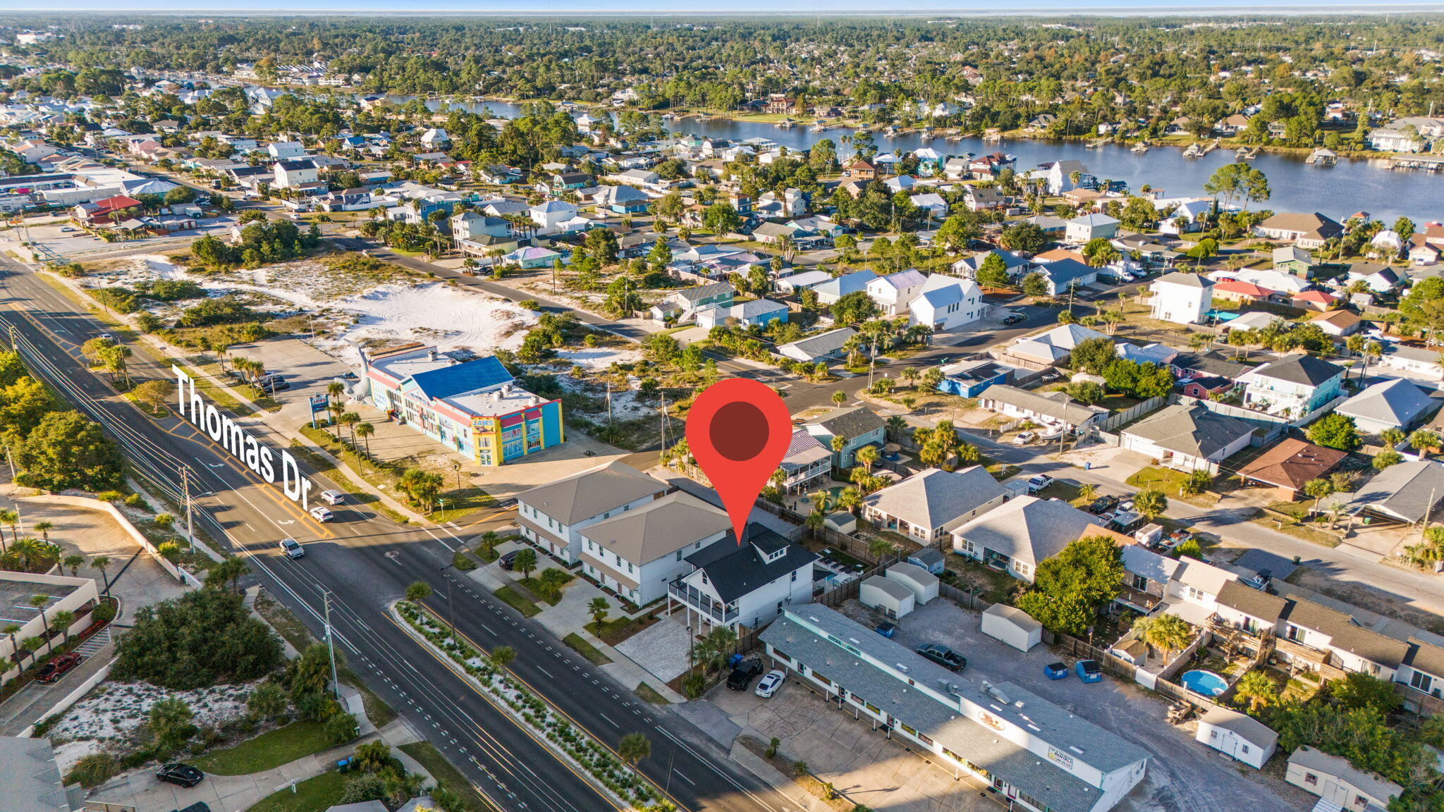 Aerial view of the Thomas Drive property marked among neighborhood homes, with waterways in the distance.