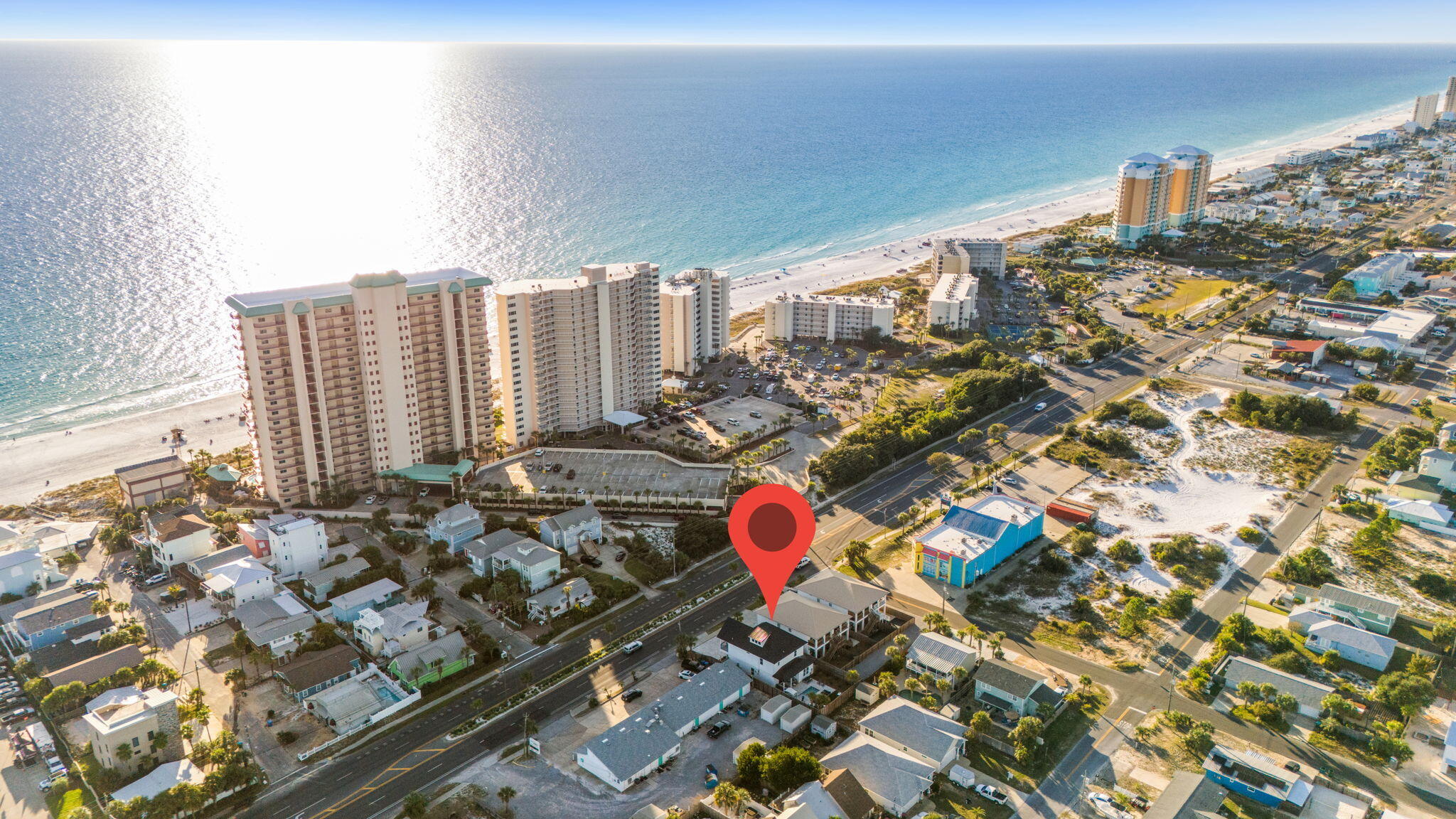 Aerial view of coastal homes along Thomas Drive, with beachfront condos and the Gulf beyond.