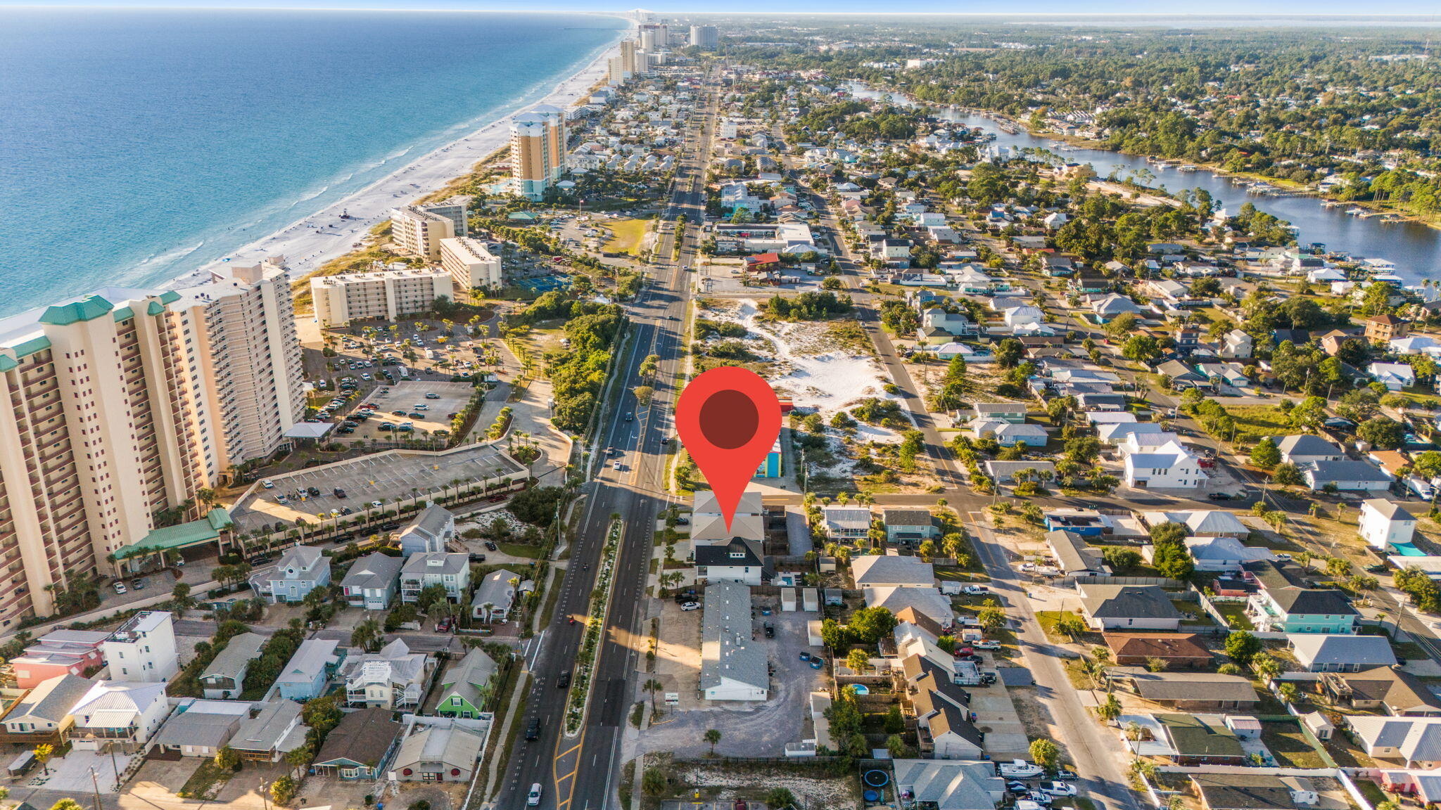 Aerial view of the property marked by a red pin near Thomas Drive, the beach, and Gulf shoreline.
