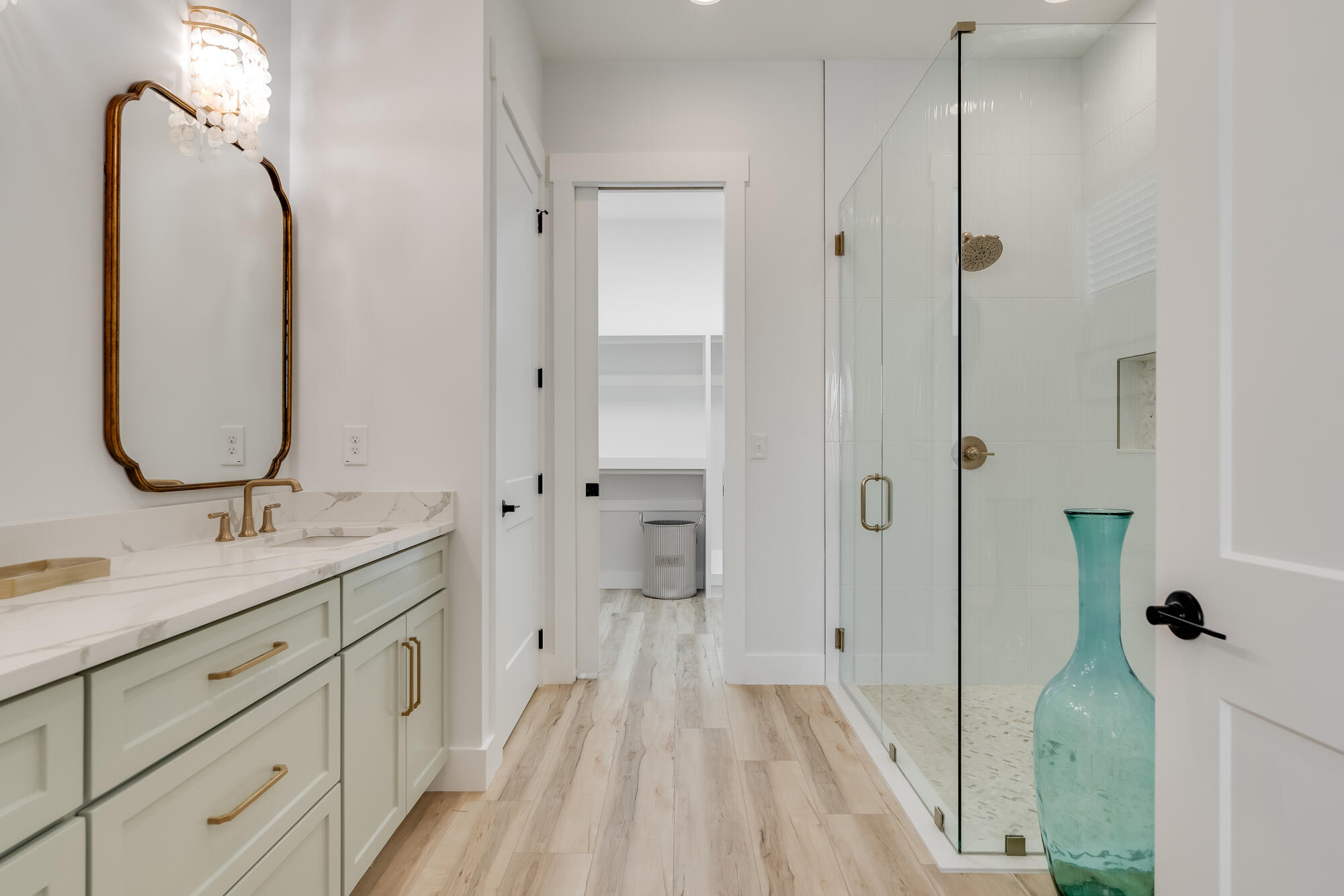 Modern bathroom with a brass-accented vanity and glass-enclosed walk-in shower.