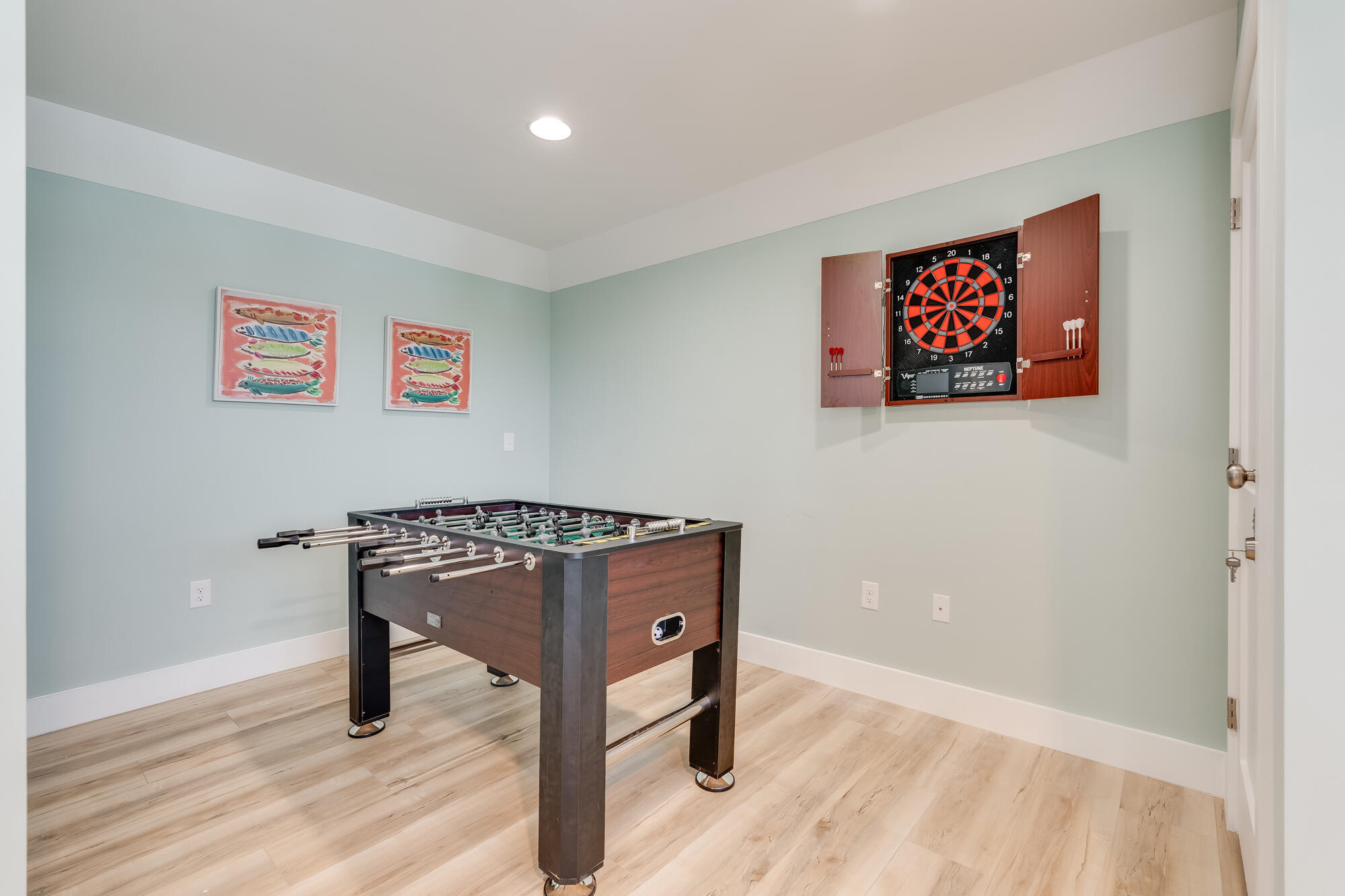 Game room with a foosball table and wall-mounted electronic dartboard.