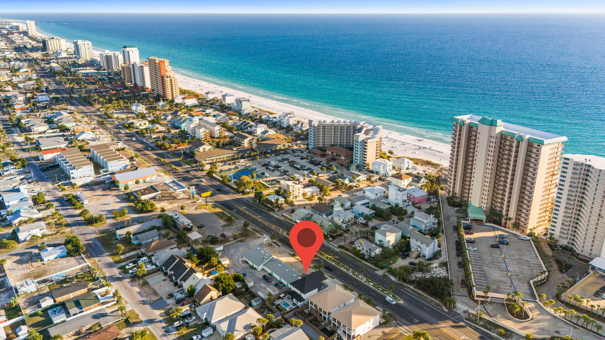 Aerial view of a Panama City Beach neighborhood, with a red pin marking a home near the beachfront.