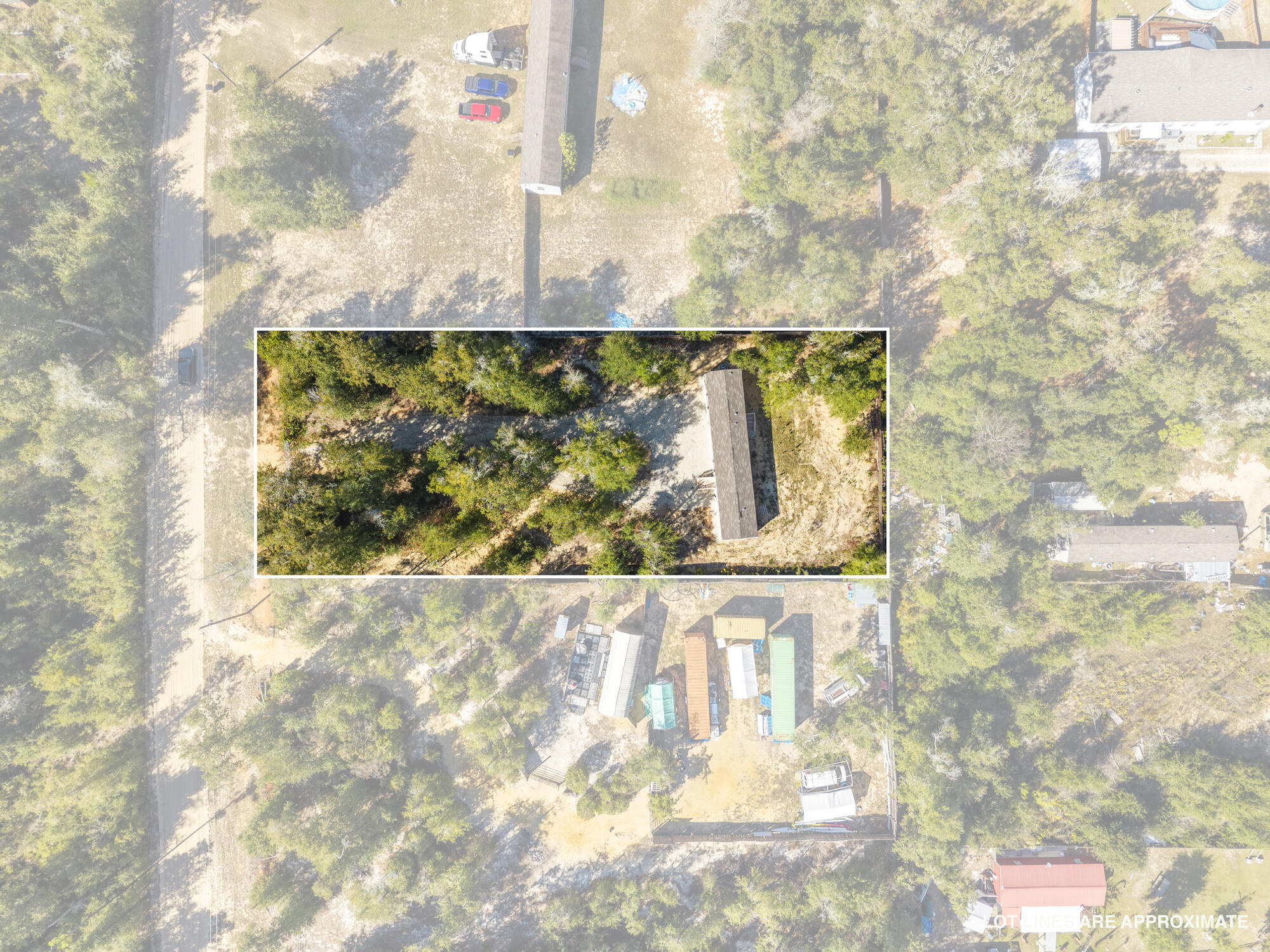 Aerial view of a wooded property outlined in white, with a long-roofed building among the trees.