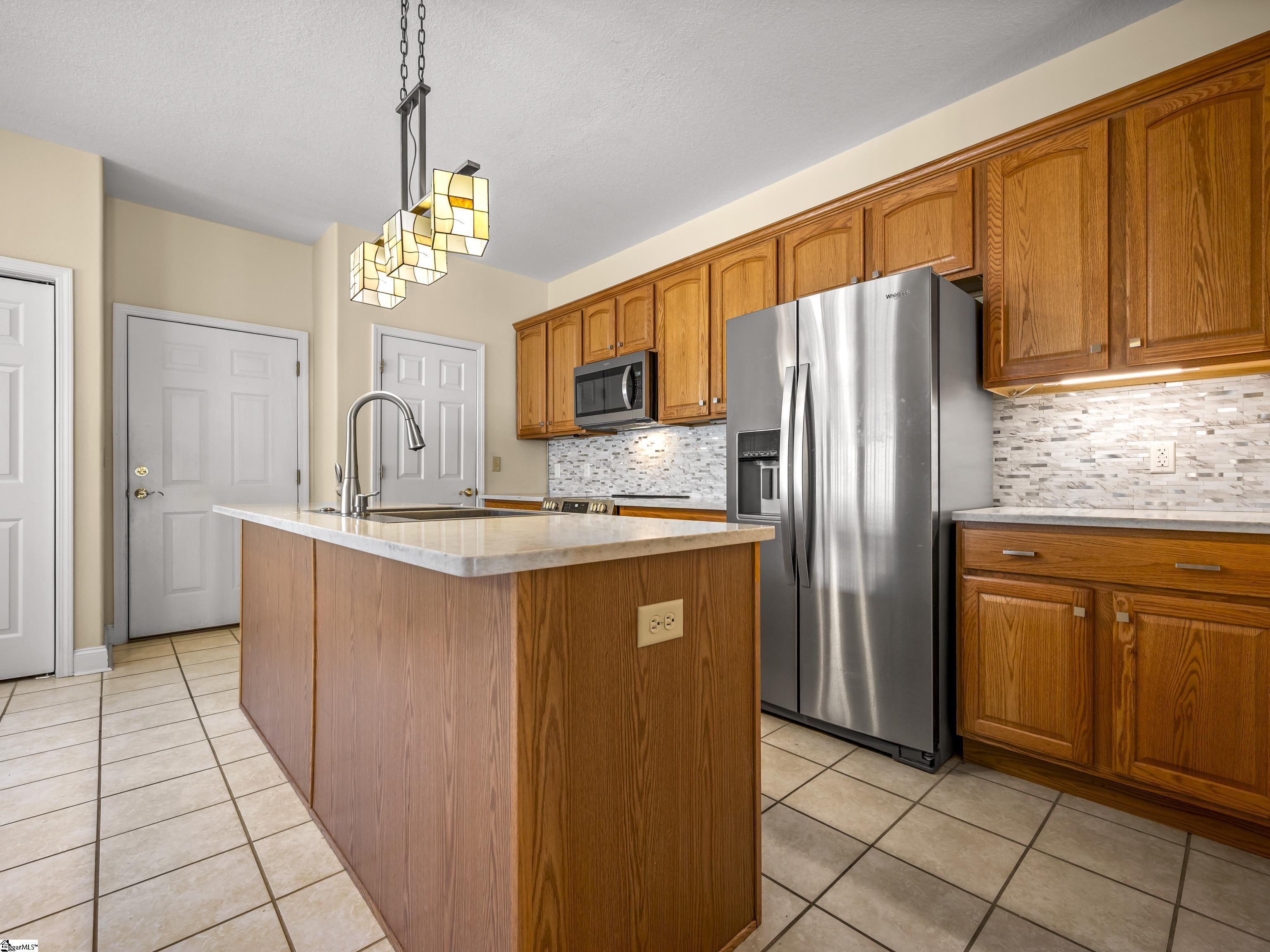 Kitchen with a large wood-paneled island, warm wood cabinets, and stainless steel appliances.