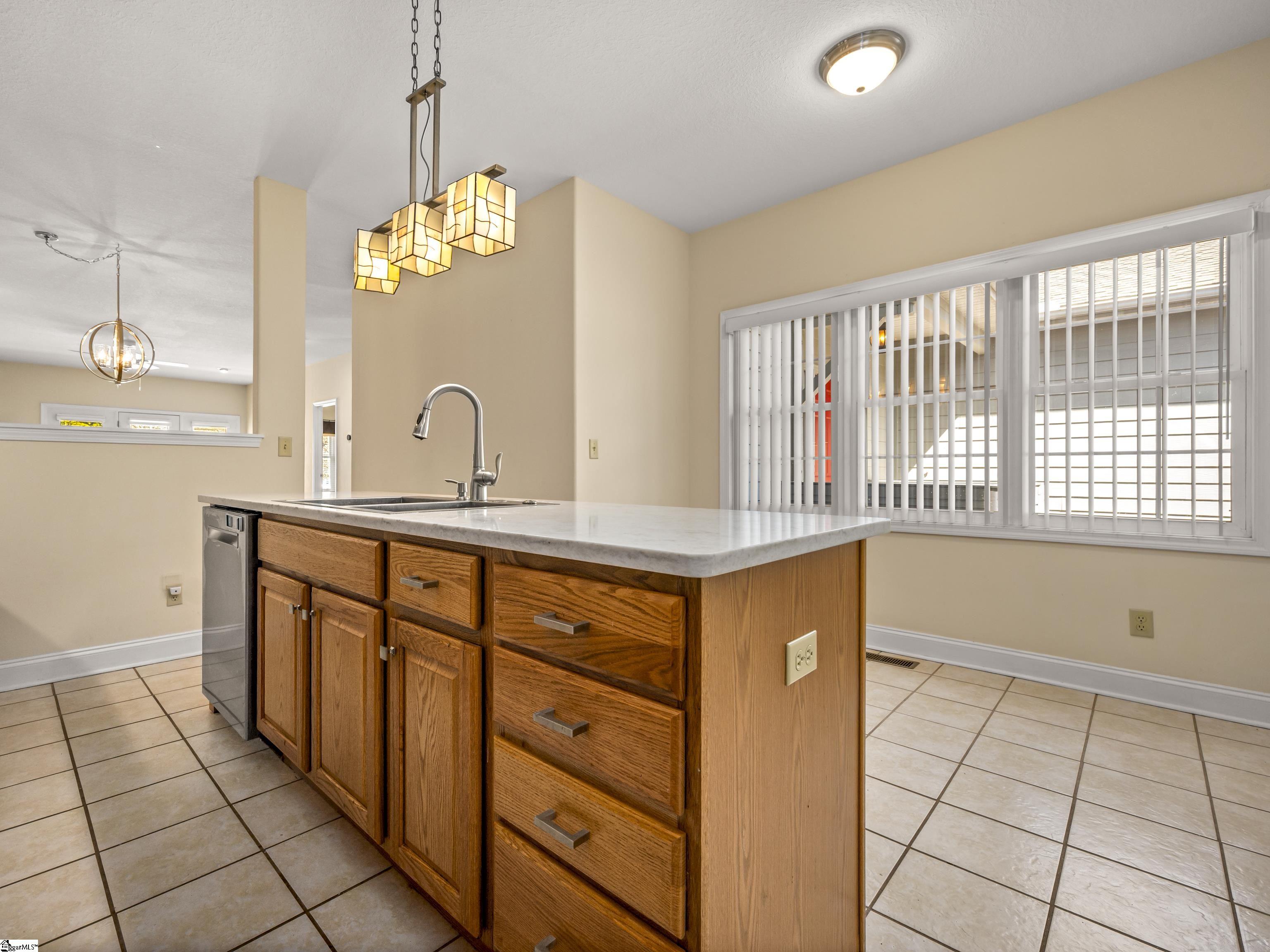 Kitchen with a large wood-paneled island, pale countertop, tall faucet and geometric pendant lights.