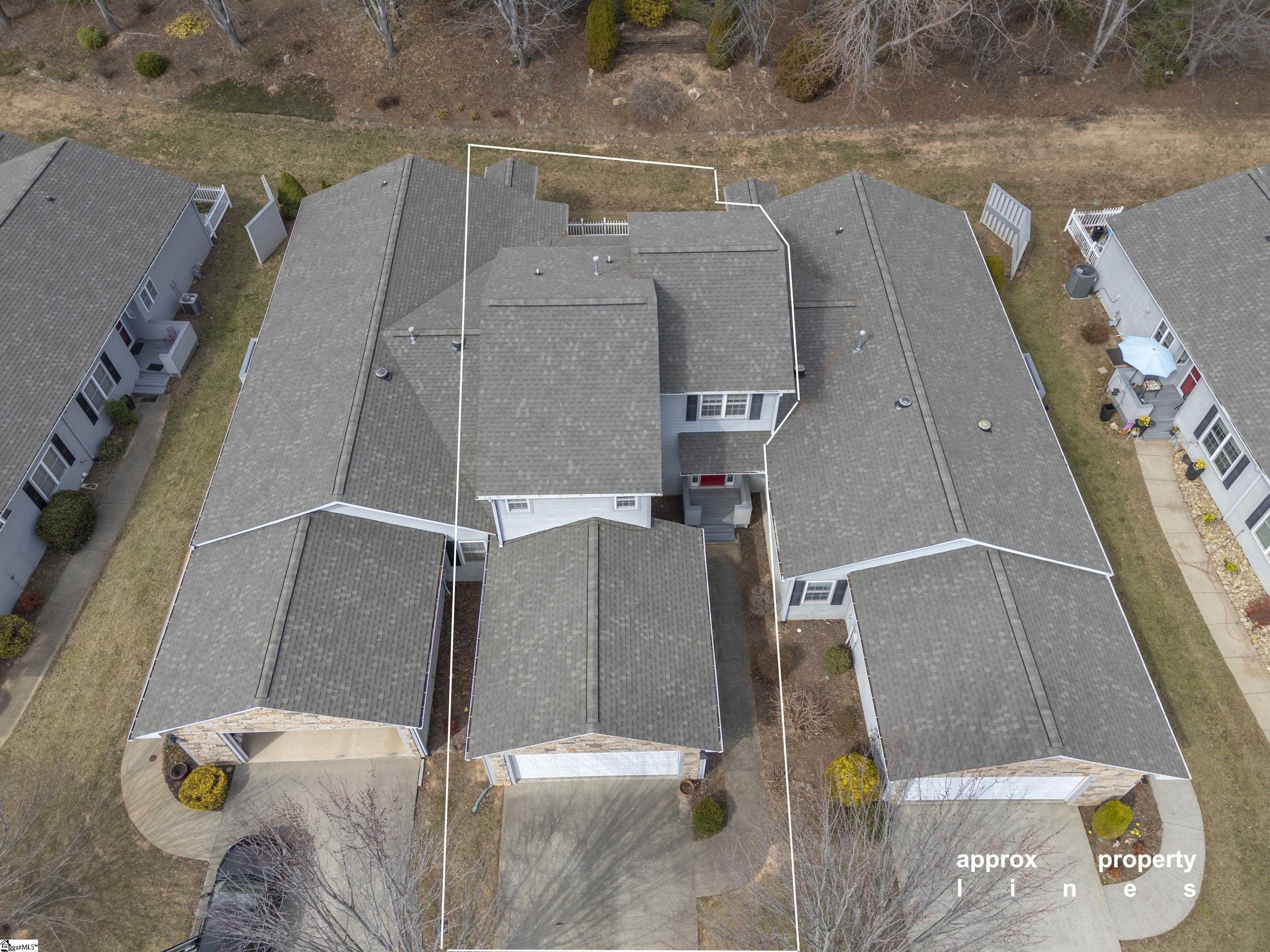 Aerial view of a home outlined by approximate property lines, with neighboring houses on both sides.