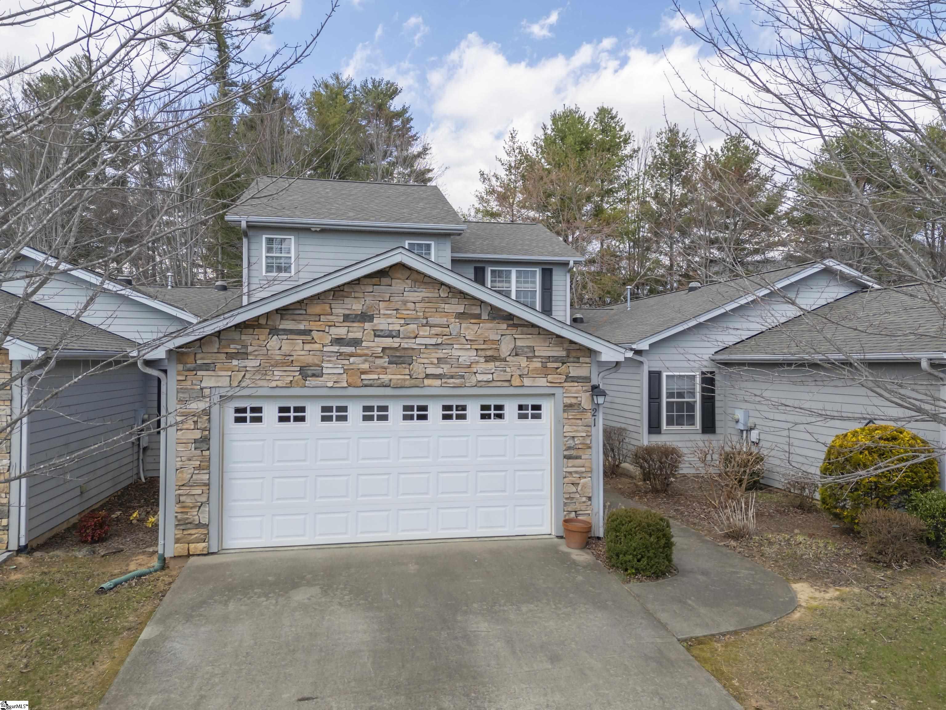 Gray two-story house with a stone-faced garage gable and broad concrete driveway.