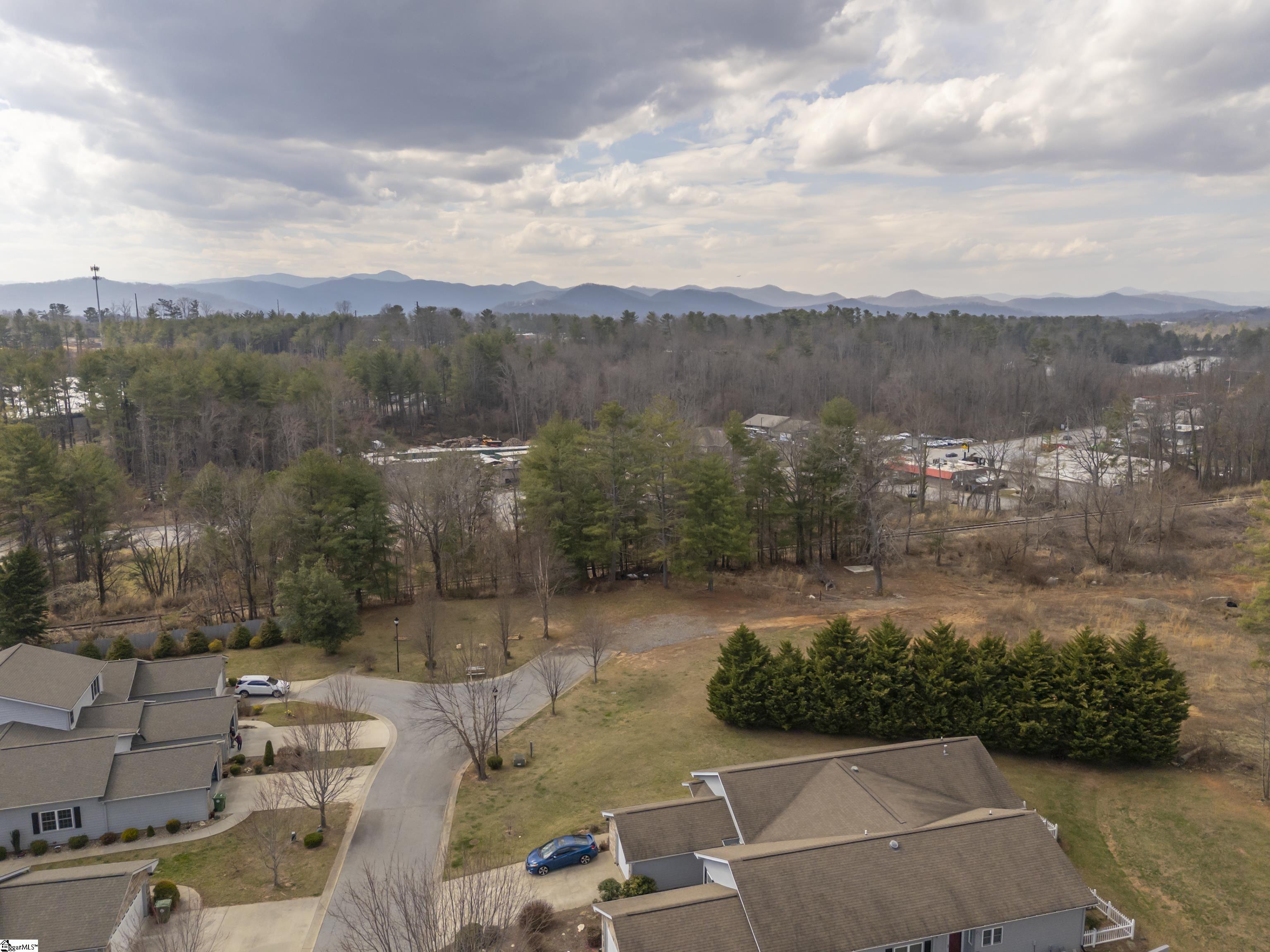 Aerial view of neighborhood homes, wooded landscape, and distant mountain ridges.