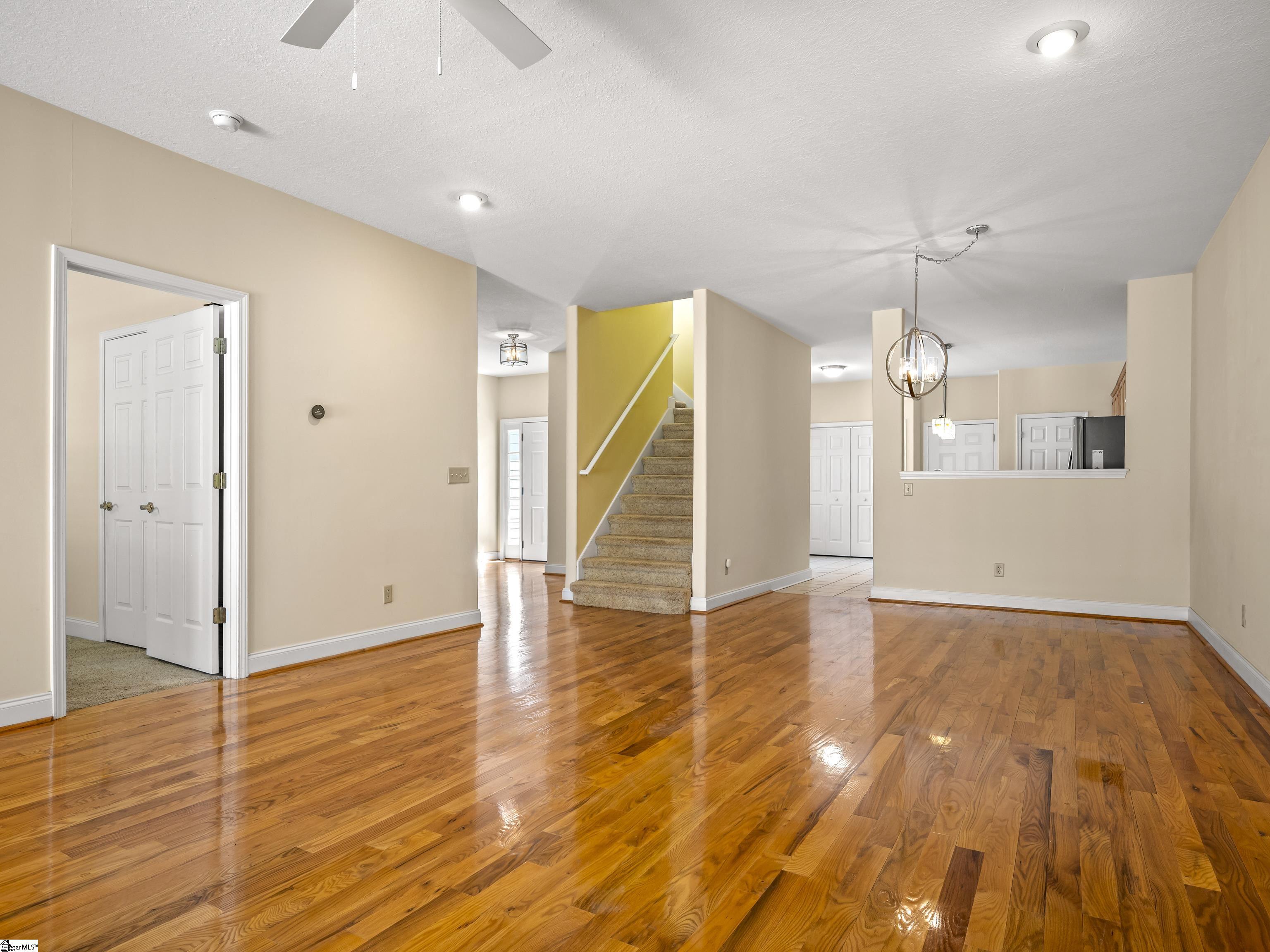 Open entry with glossy hardwood floors, a carpeted staircase, and a kitchen pass-through.