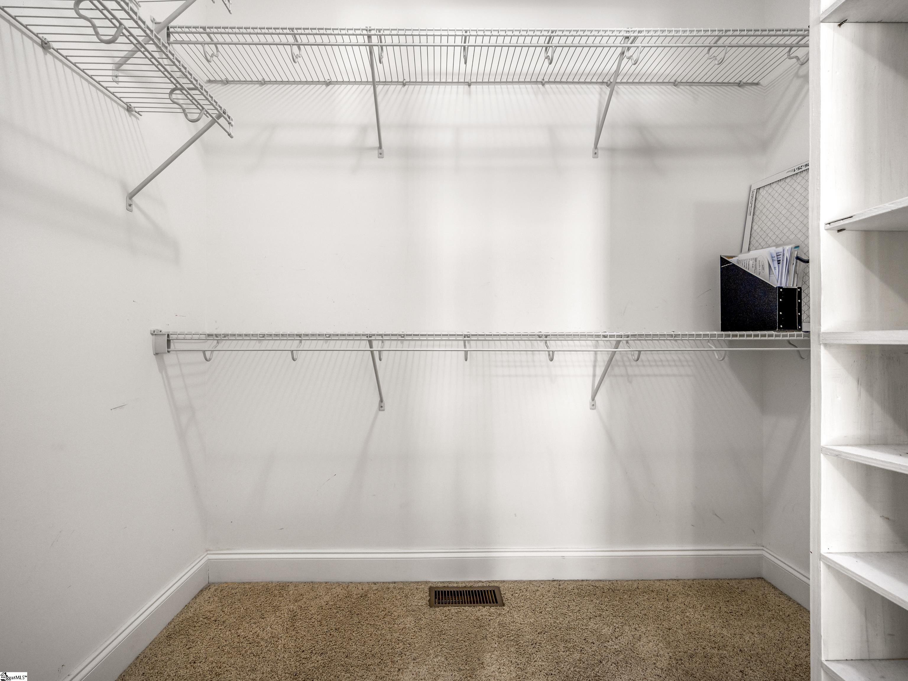 Walk-in closet with wire hanging shelves, beige carpet, and built-in shelving.