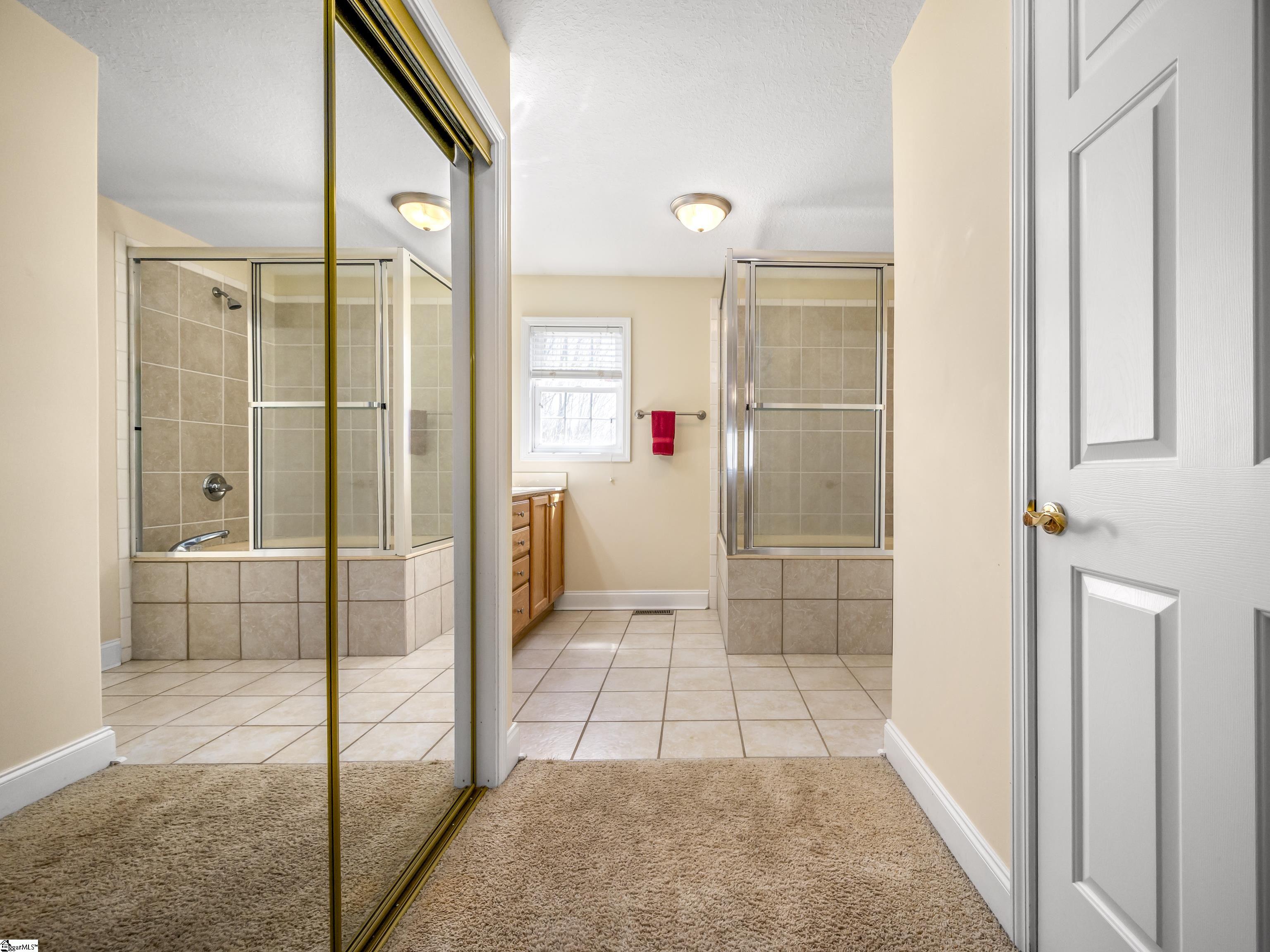 Bathroom with two glass-enclosed tiled showers and mirrored sliding closet doors.