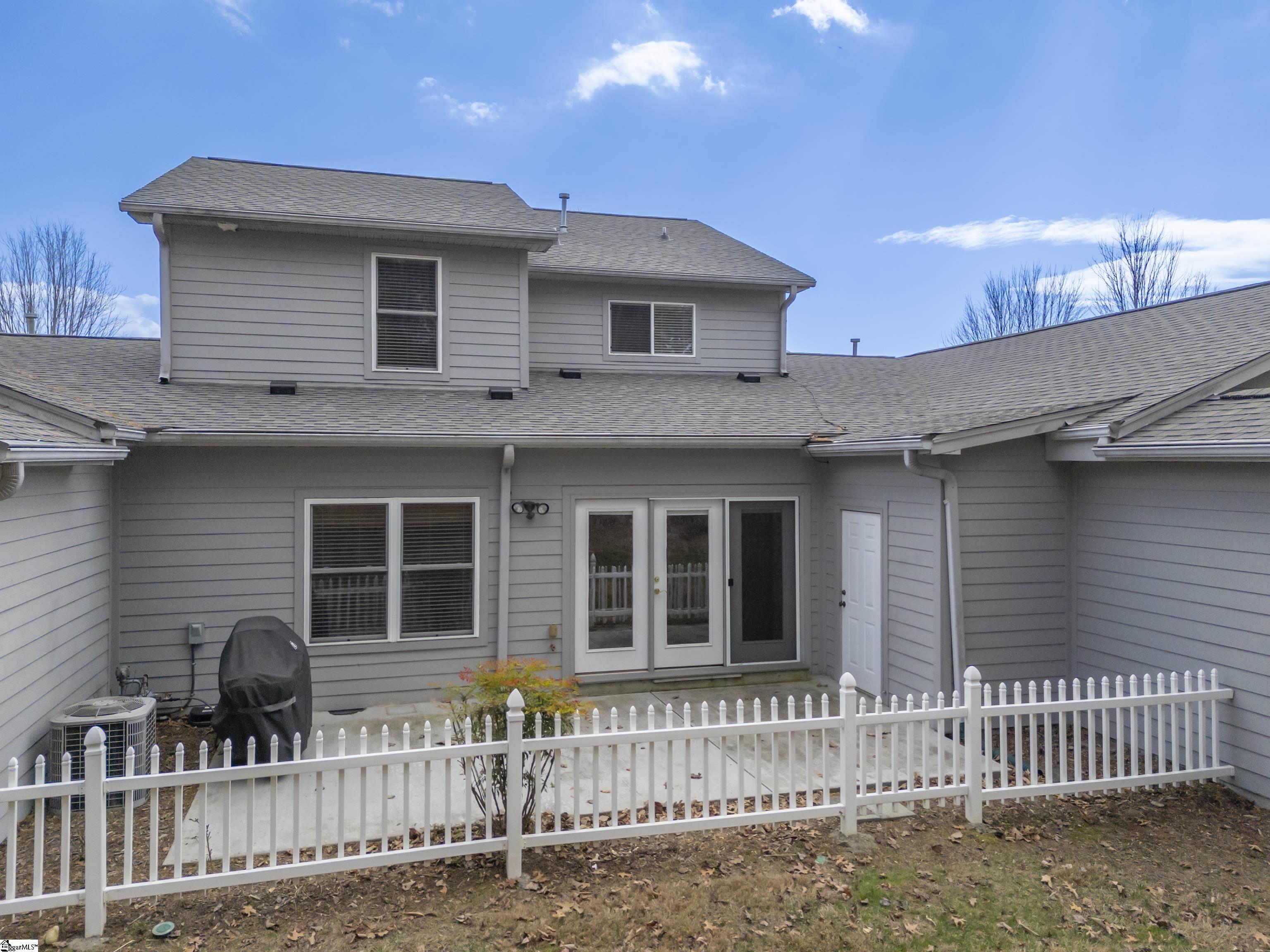 Gray two-story home with a white-fenced patio and sliding glass doors.