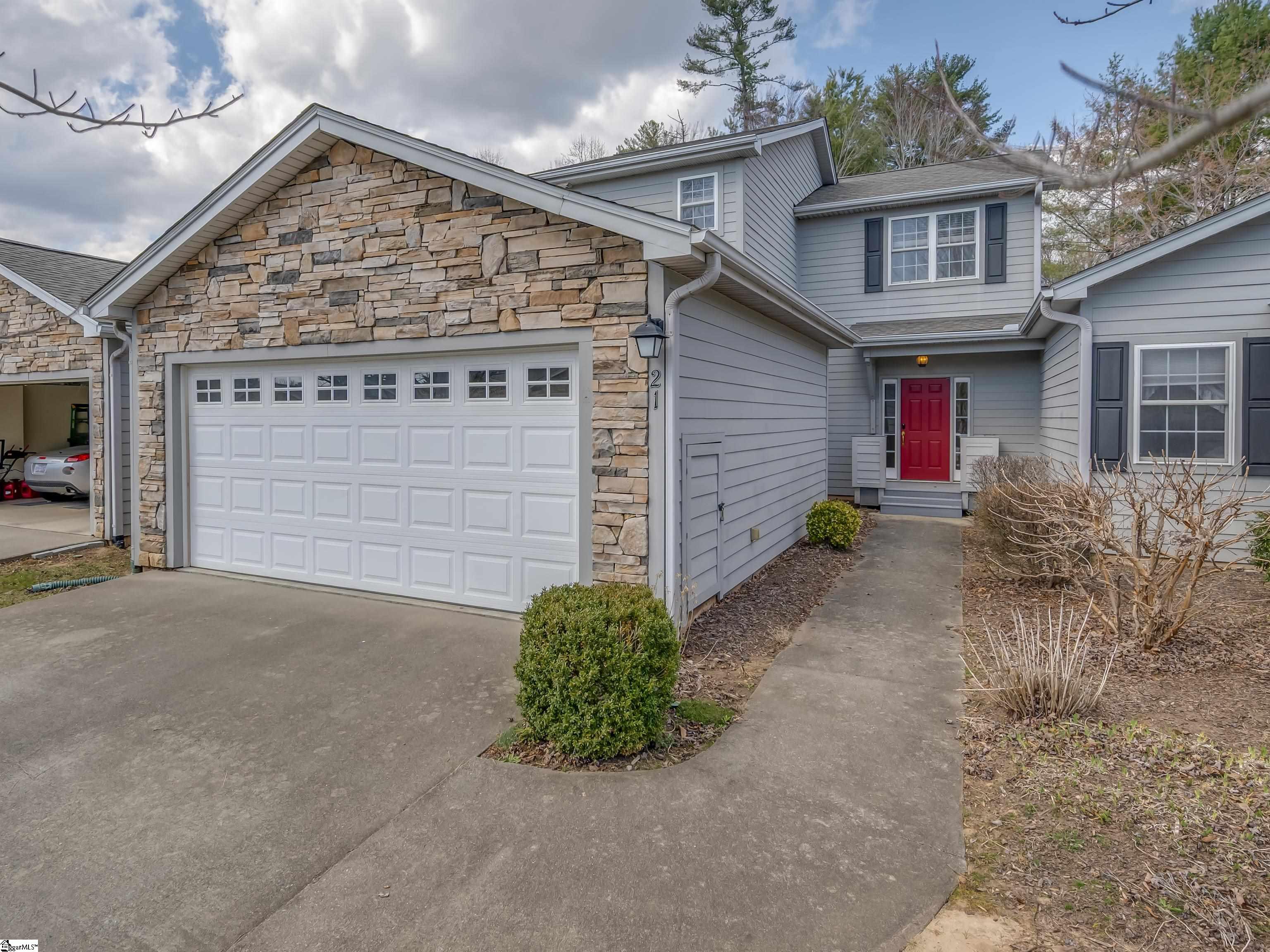 Gray two-story house with a stone garage facade, red front door, and concrete driveway.