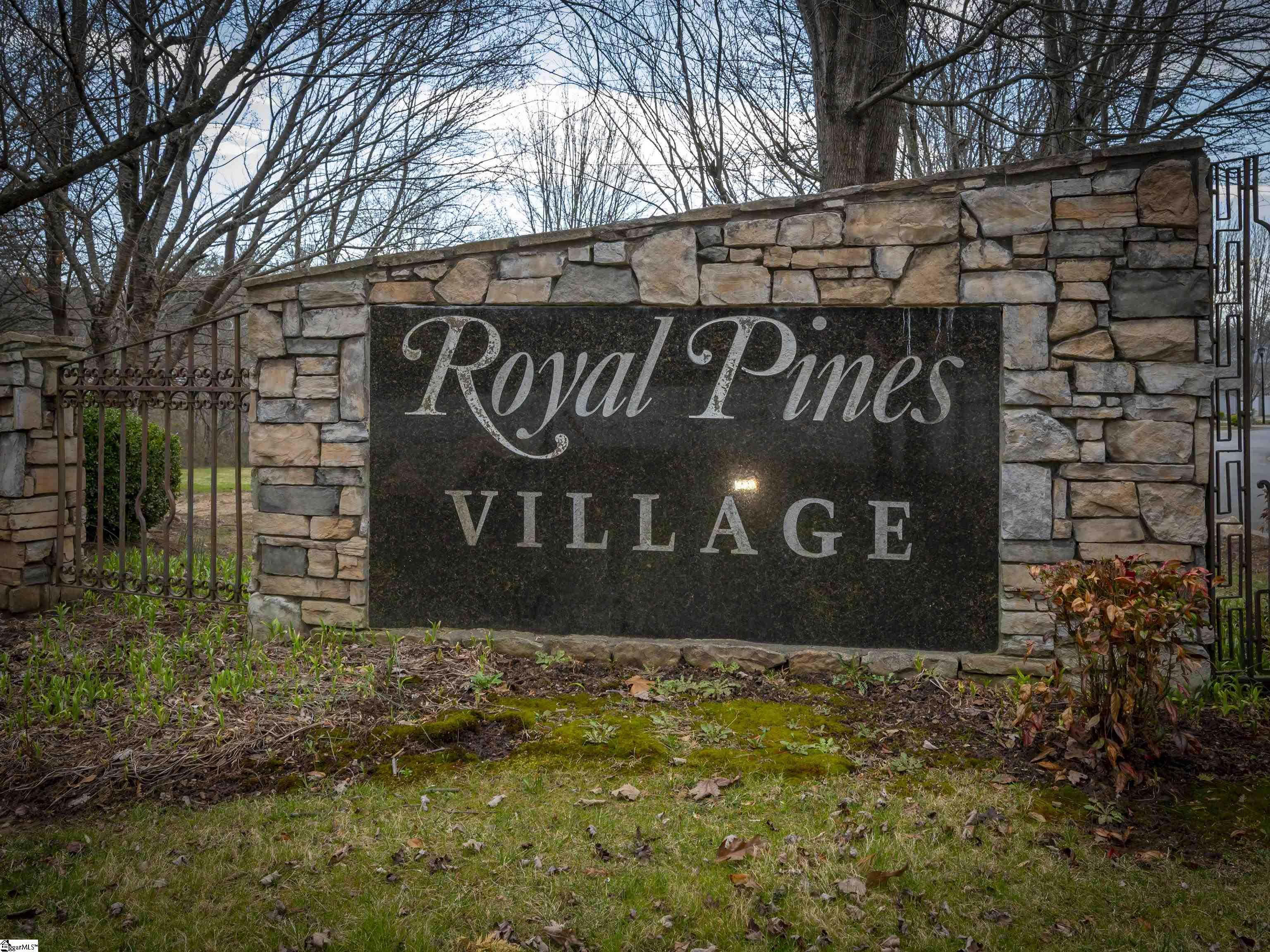 Stone entrance monument for Royal Pines Village beside wrought-iron gates.