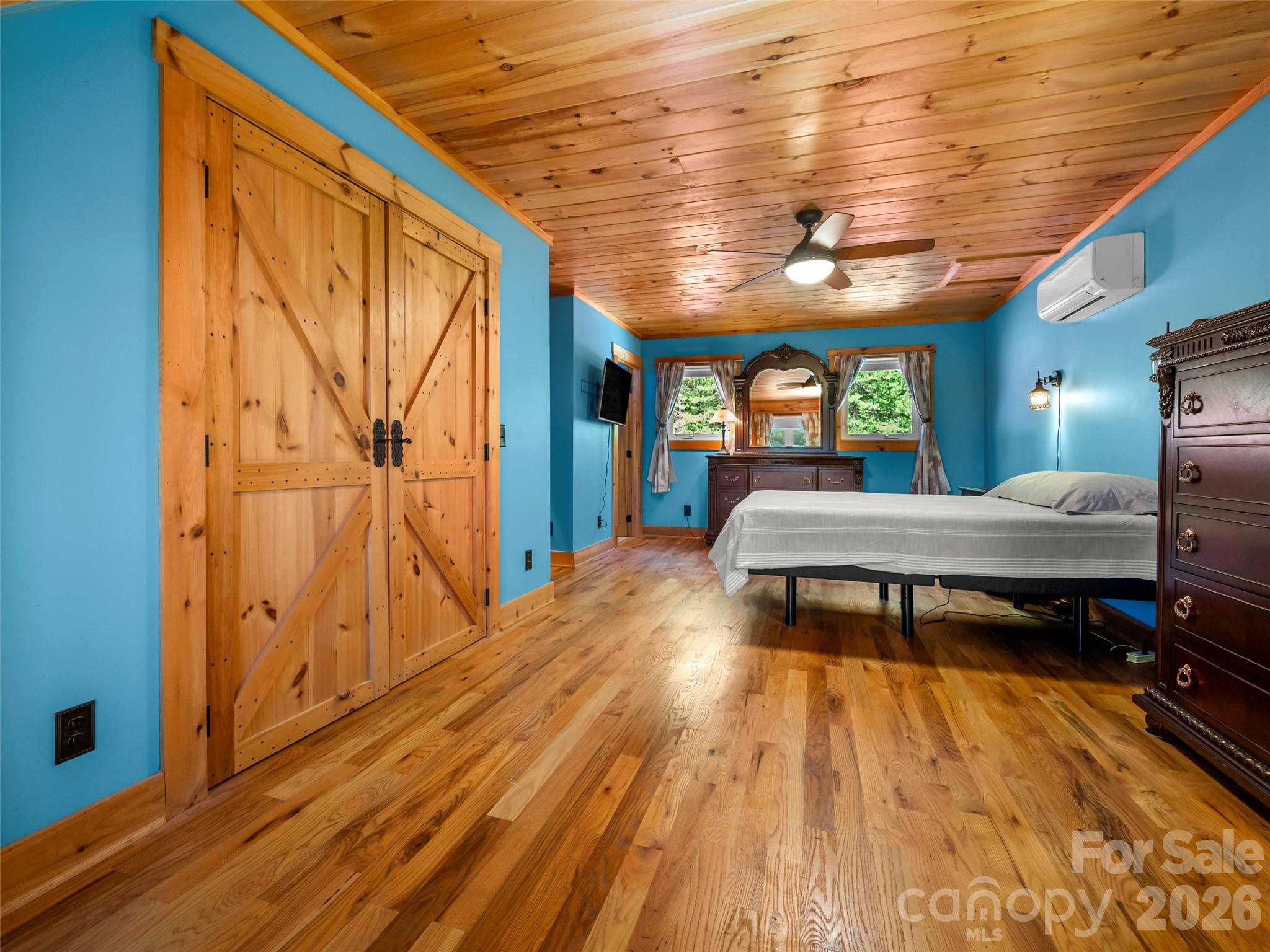 Bedroom with blue walls, wood plank ceiling and floor, and rustic sliding barn doors.
