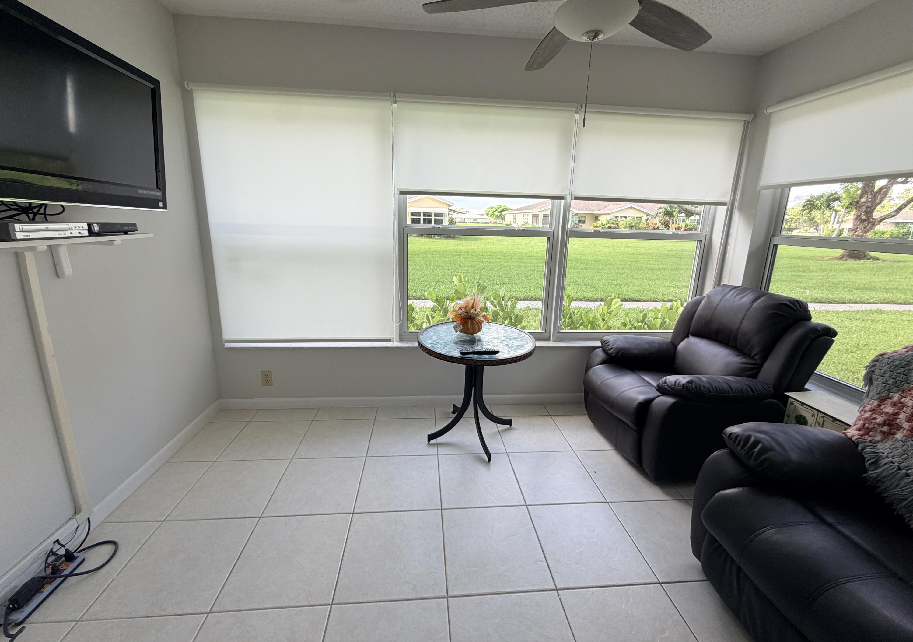 Furnished living room with leather recliners and wide windows overlooking a green lawn.