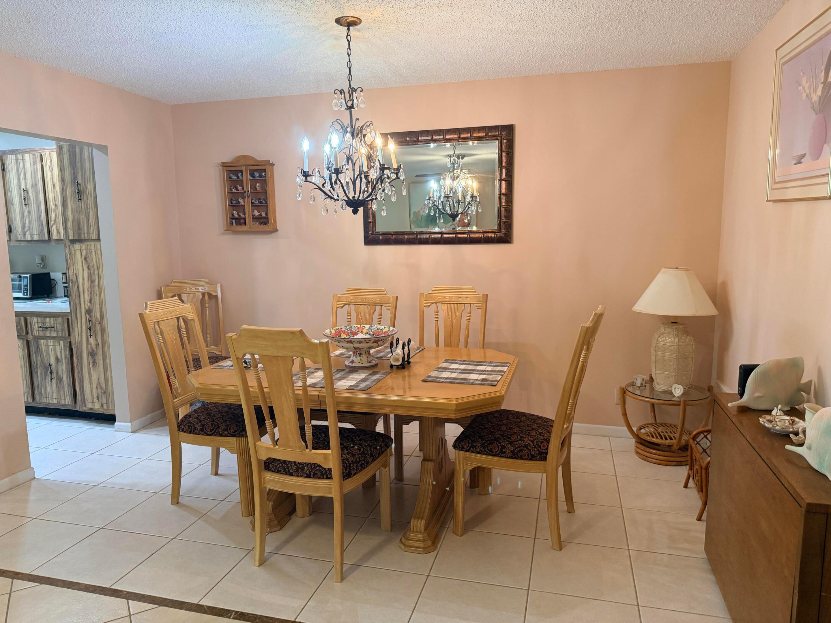 Furnished dining room with a wooden table, carved chairs, and crystal chandelier.