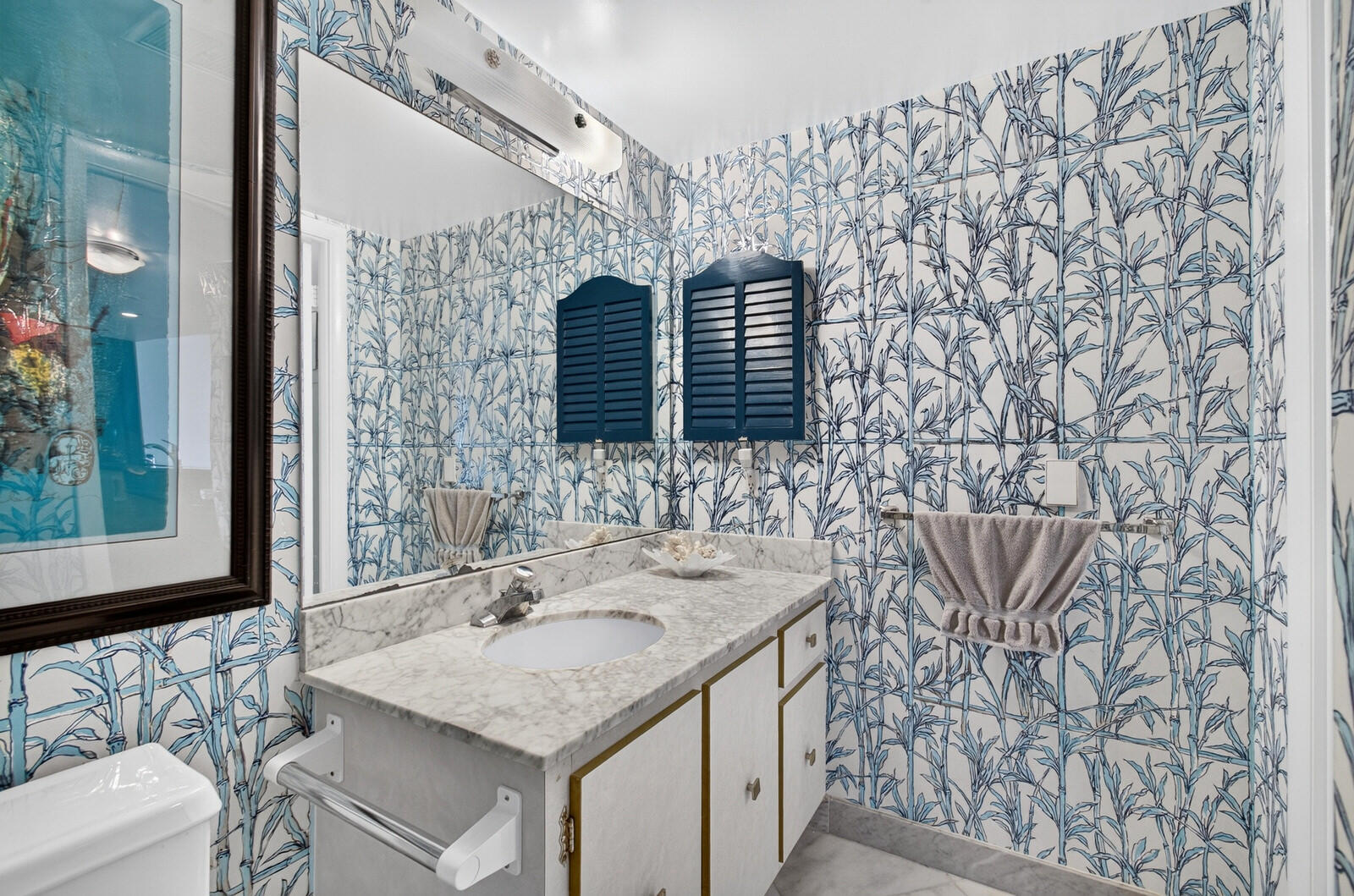 Bathroom with blue botanical wallpaper and a marble vanity with mirrored medicine cabinets.