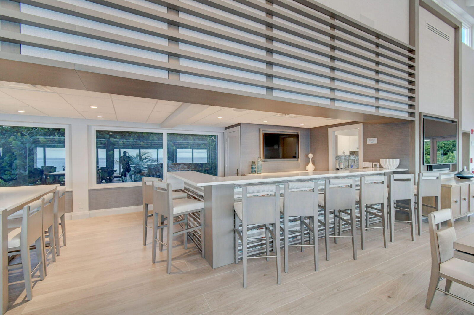 Kitchen bar with a long island, bar stools, and large windows overlooking the water.