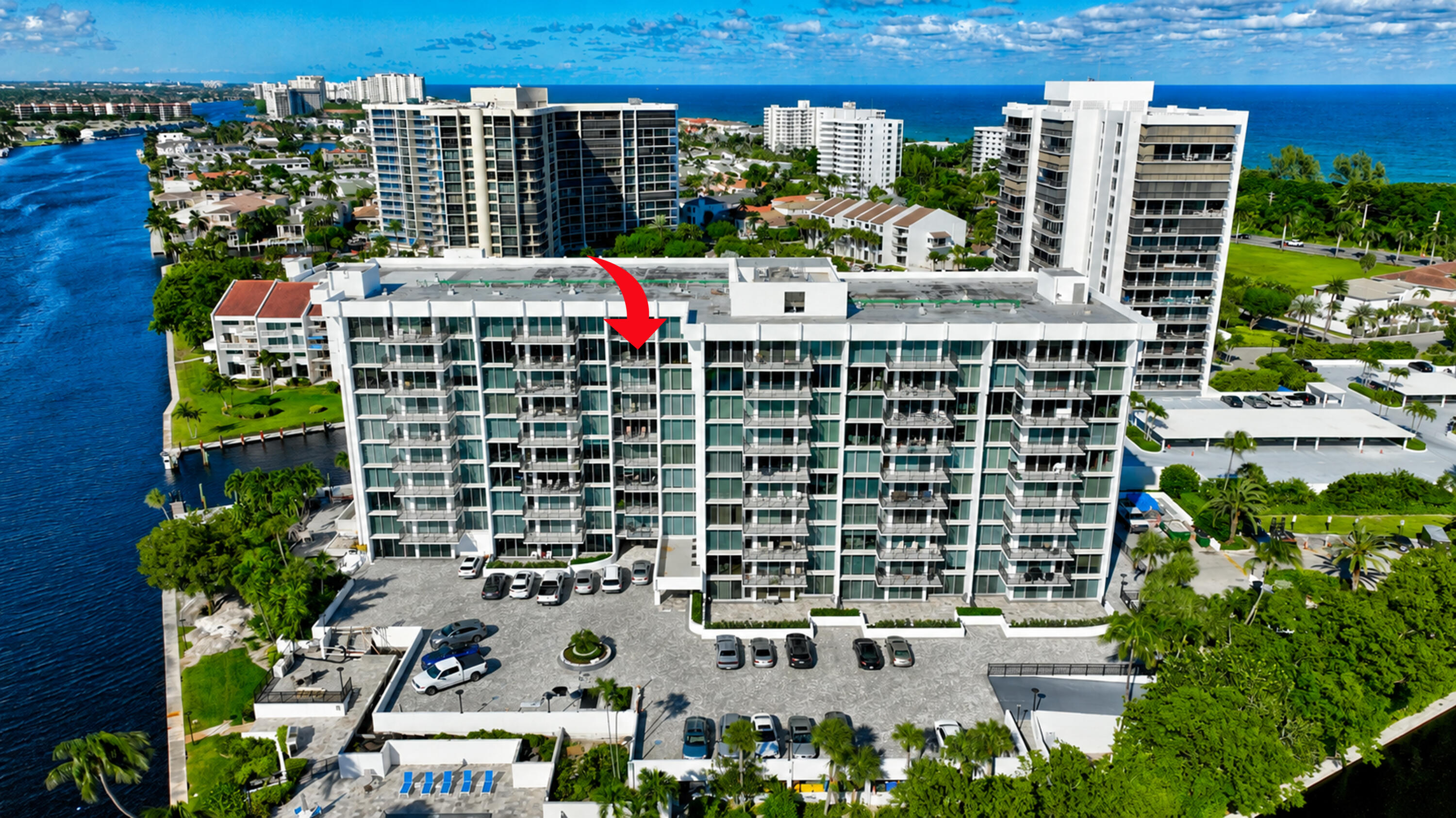 Aerial view of the waterfront condominium, with a red arrow marking a unit on its facade.