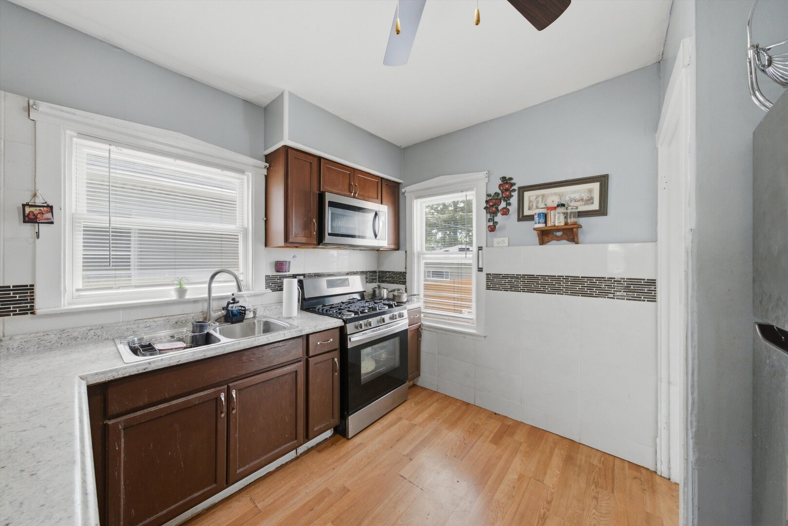 Kitchen with dark wood cabinets, stainless steel appliances, double sink, and wood-look flooring.