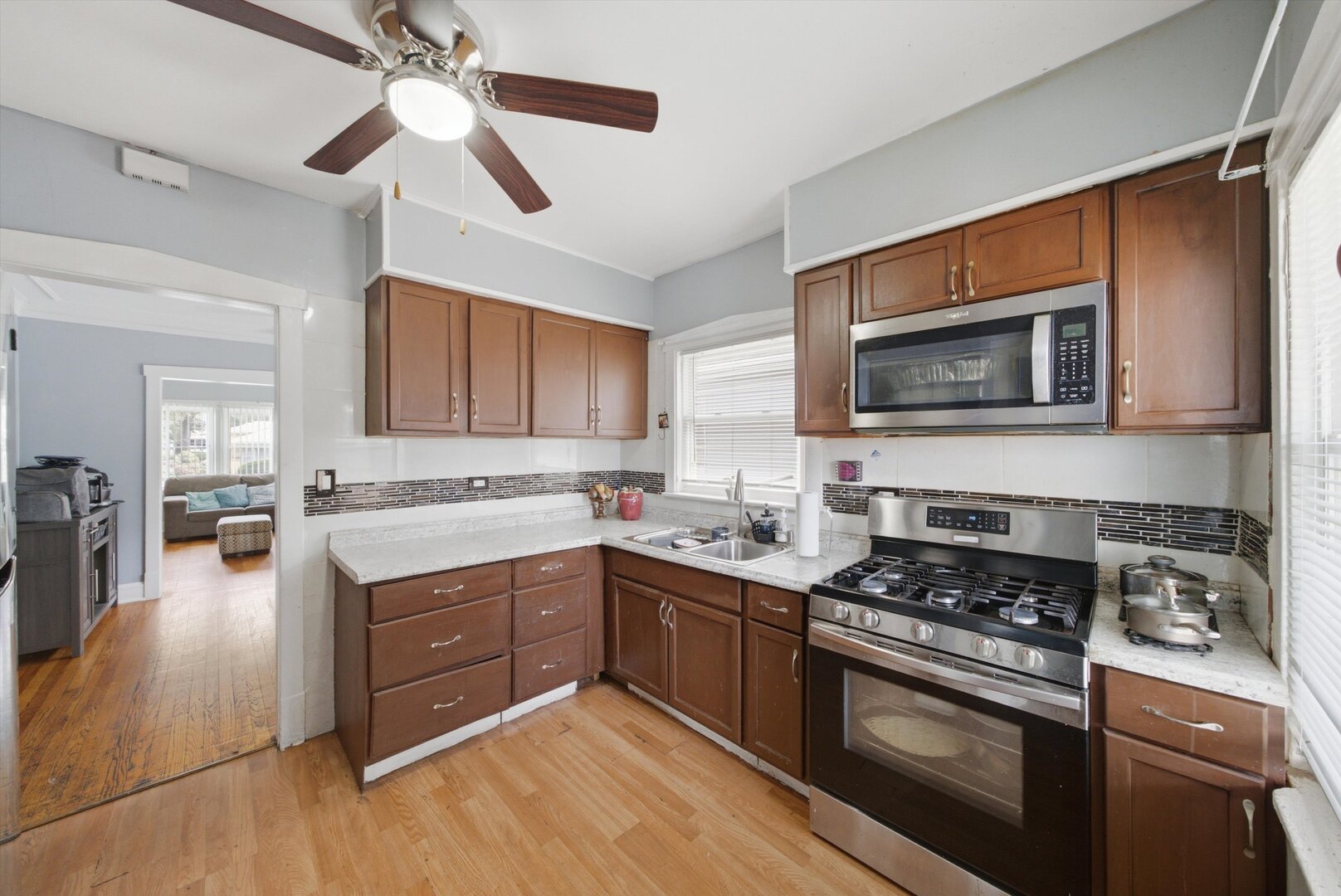 Kitchen with wood cabinets, stainless steel appliances, mosaic tile backsplash, and hardwood floors.