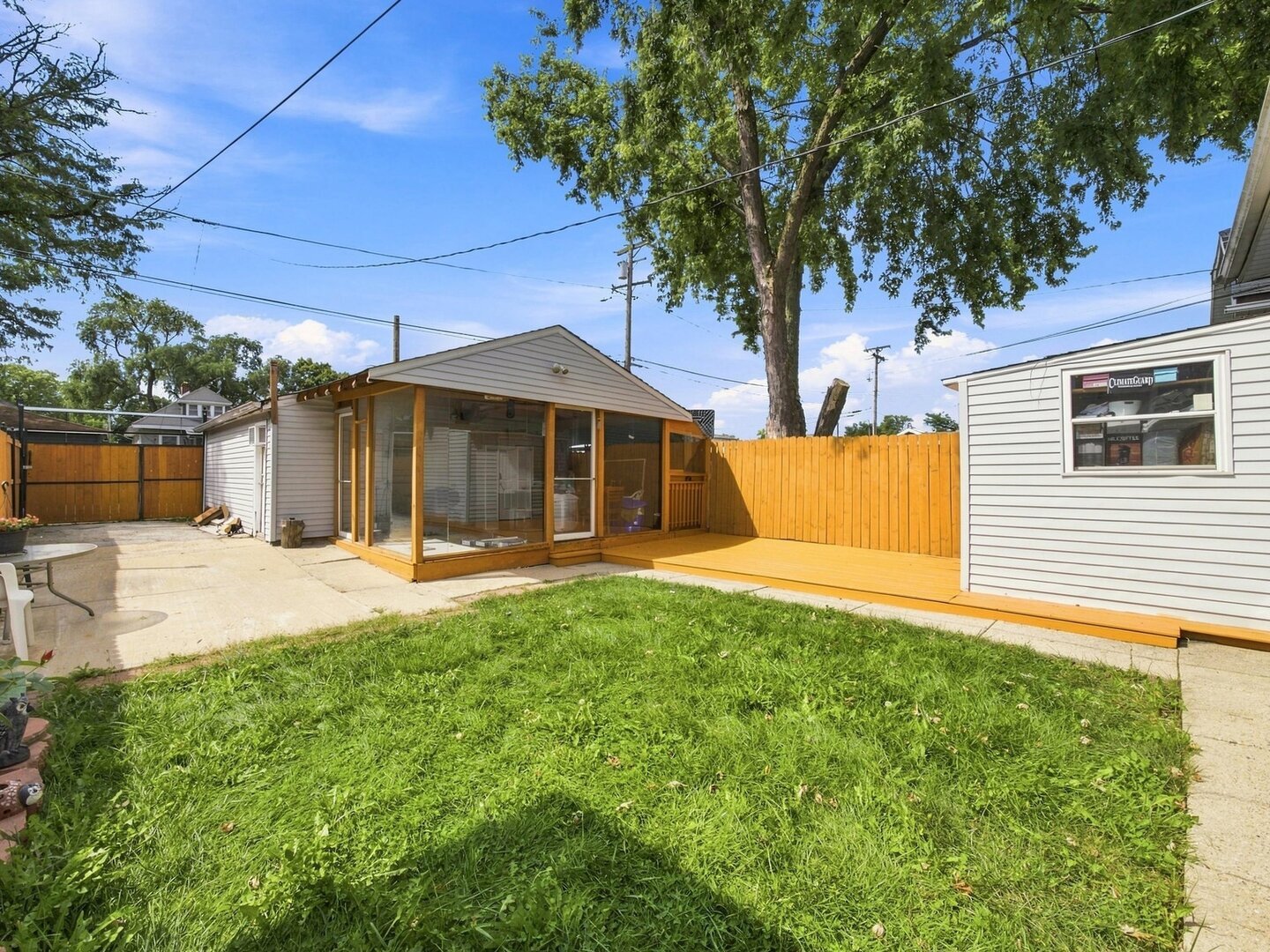 Backyard with a glass-enclosed sunroom, concrete patio, and wooden privacy fence.