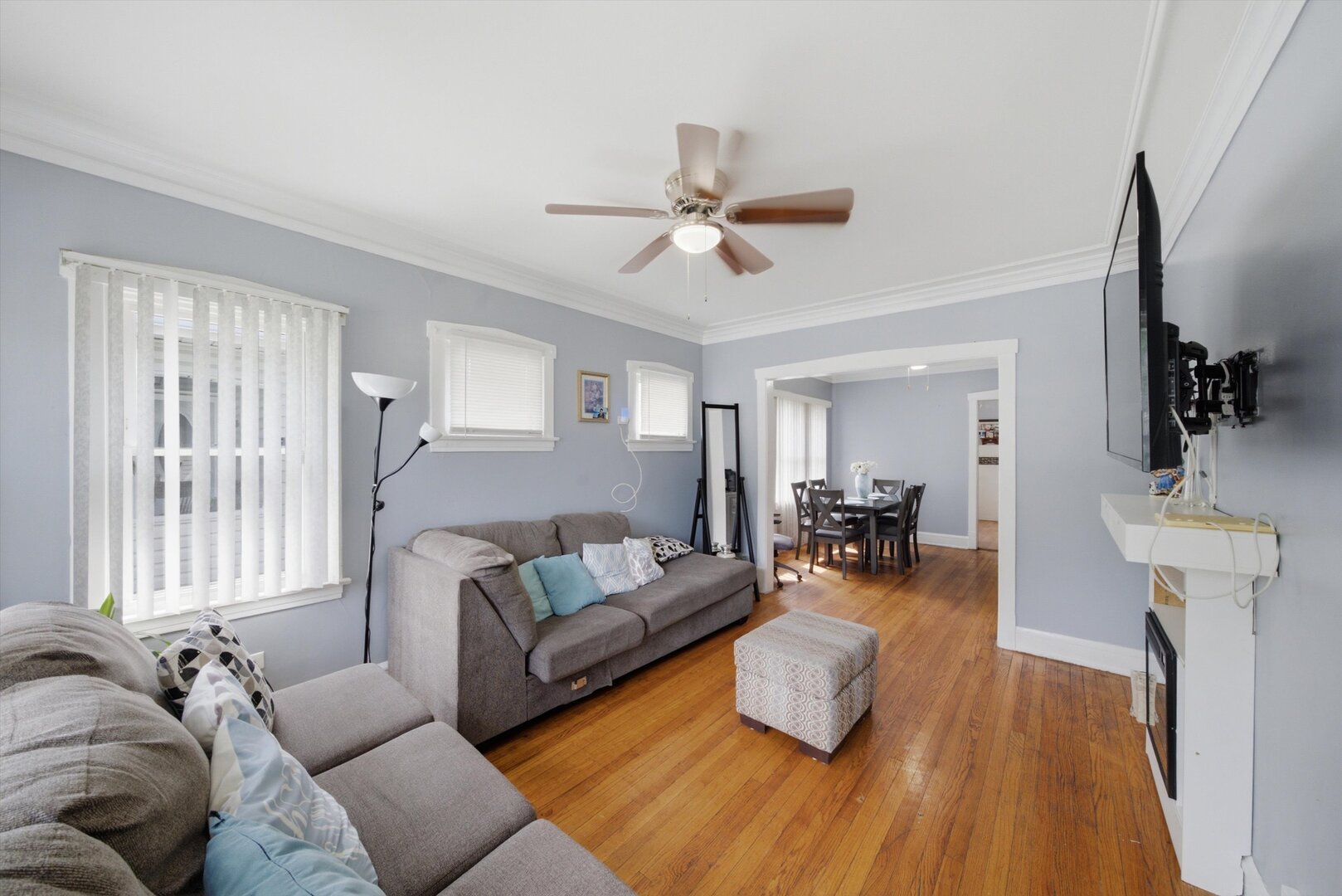 Living room with gray sofas and hardwood floors, opening into a dining area.