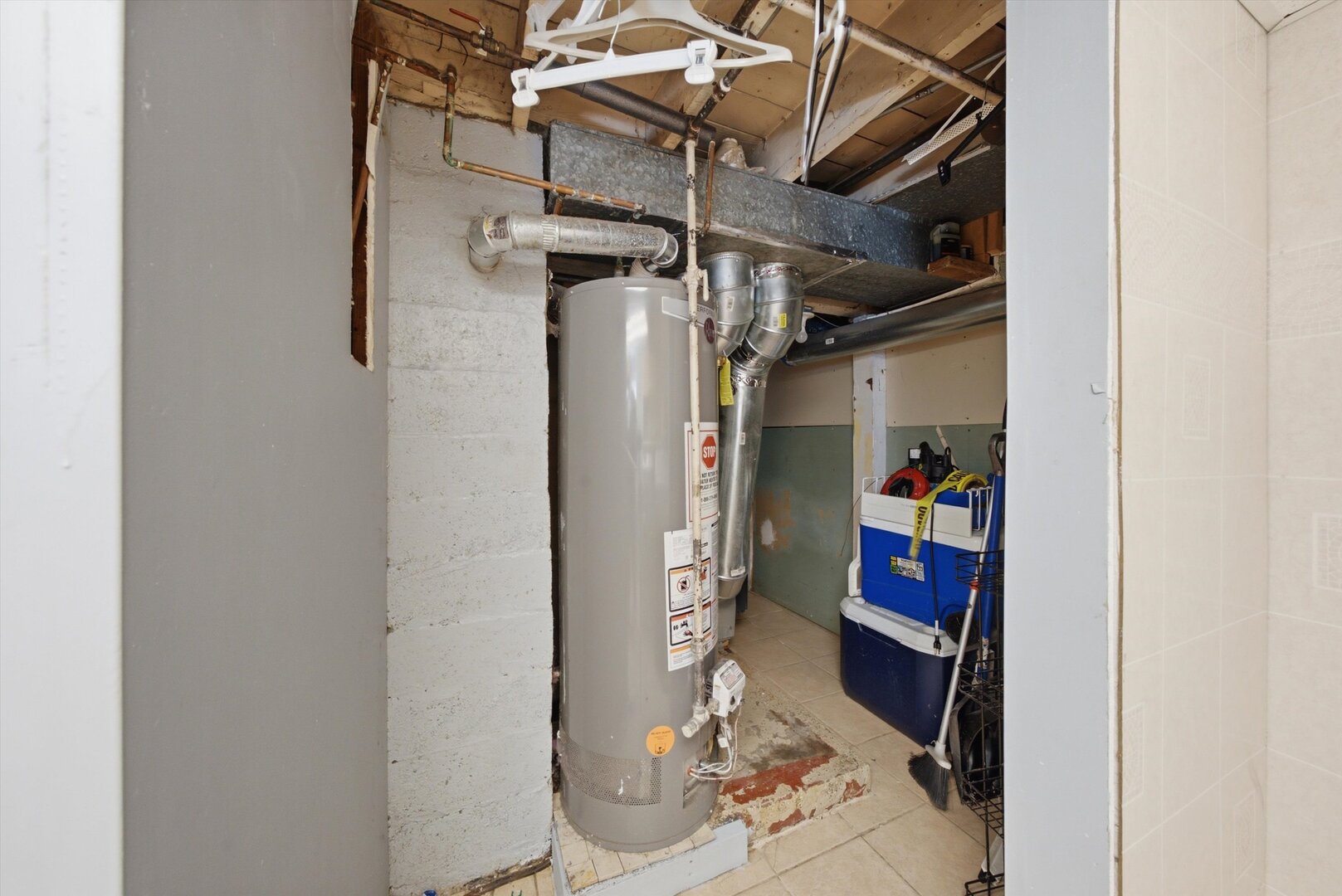 Basement utility area with a tall water heater, exposed ductwork, and unfinished ceiling joists.