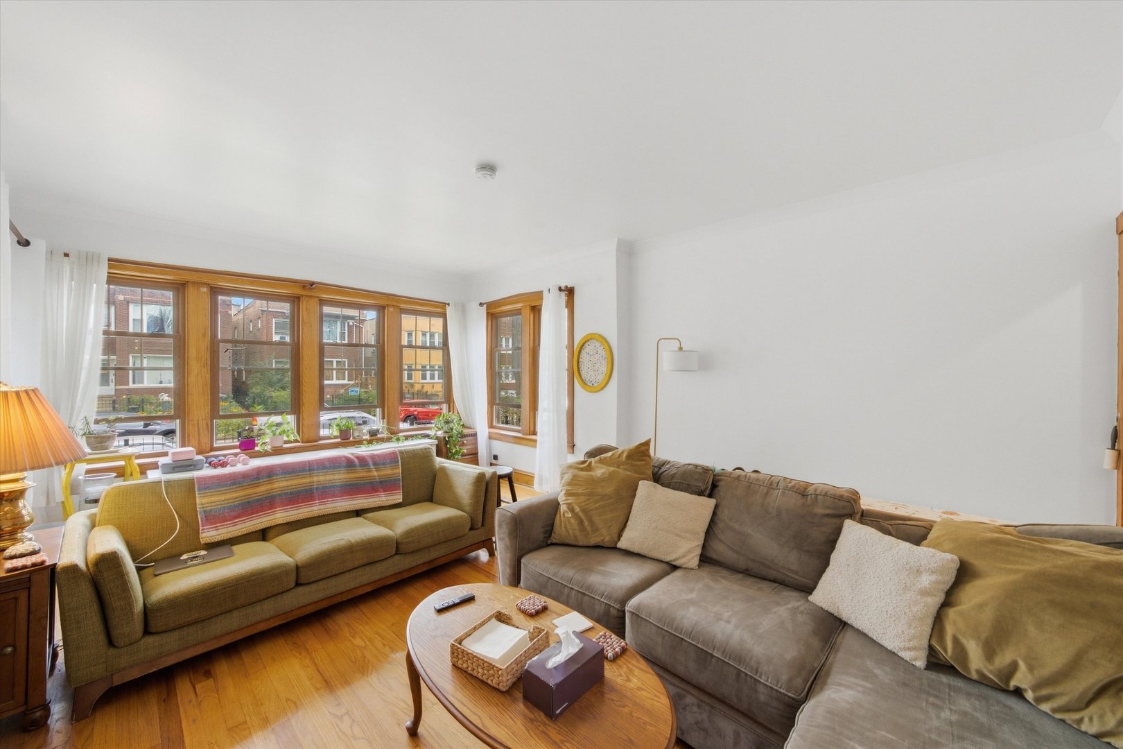 Living room with two sofas, hardwood floors, and large wood-framed windows.