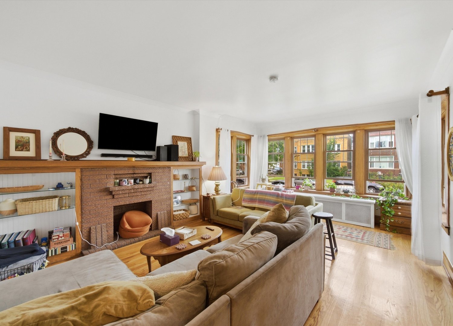 Living room with a brick fireplace, built-in shelves, and wide wood-framed windows.