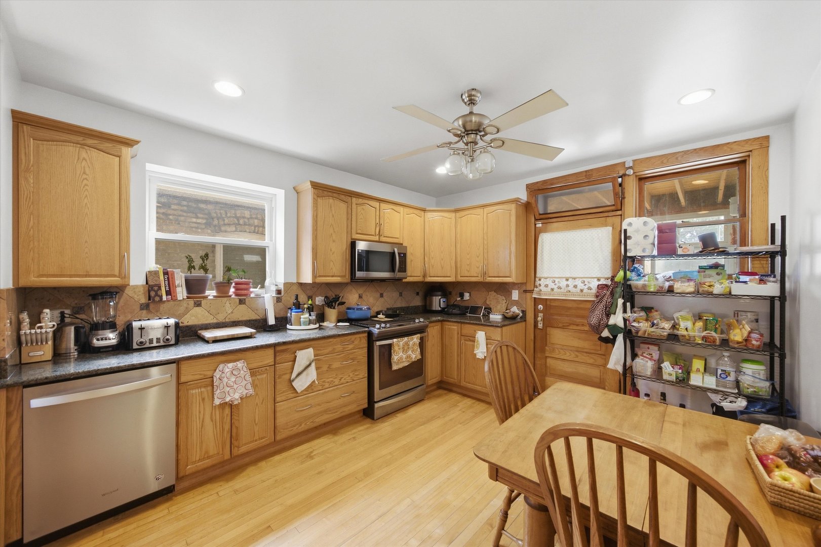 Kitchen with oak cabinets, stainless steel appliances, and a dining table beside the back door.