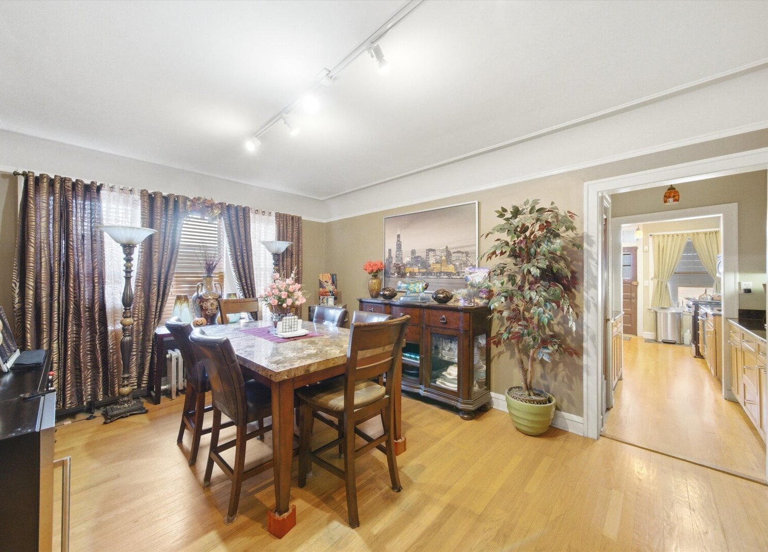 Dining room with a large wood table and chairs, hardwood floors, and a view into the kitchen.