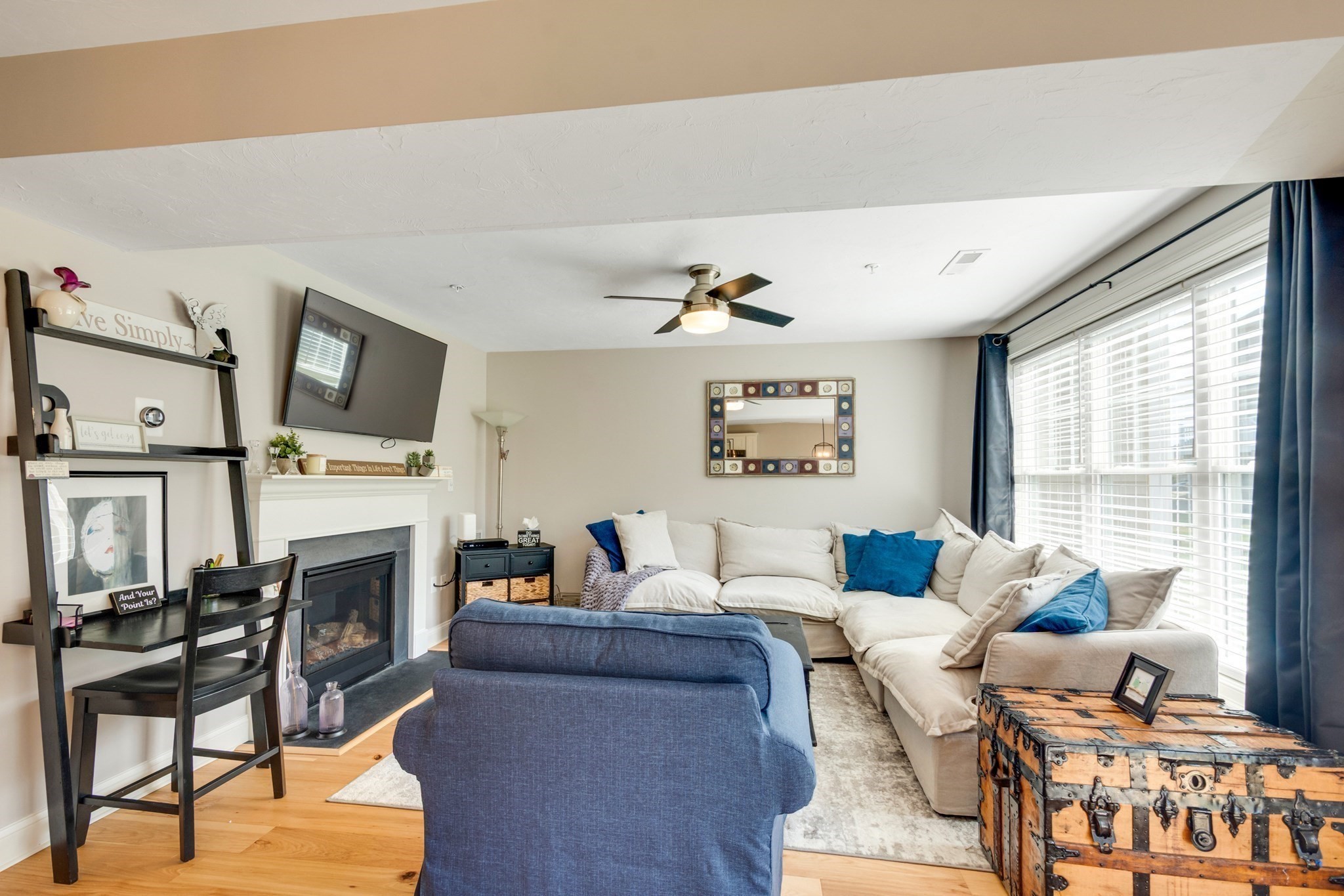 Living room with a white sectional, blue chair, fireplace, and large curtained windows.
