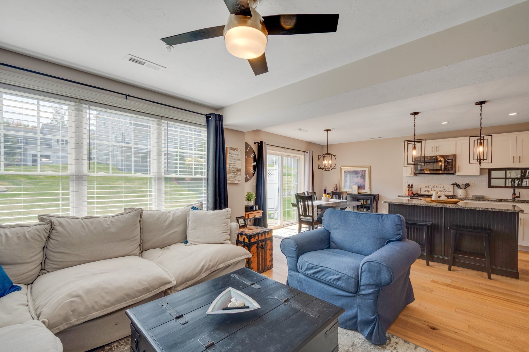 Open-plan living room with a cream sectional, blue armchair, and kitchen island.