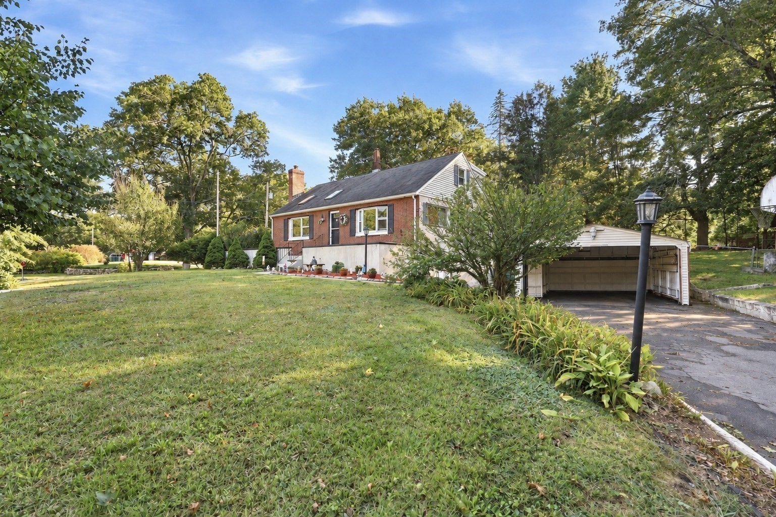 Red-brick house with a detached garage, broad lawn, and mature trees.