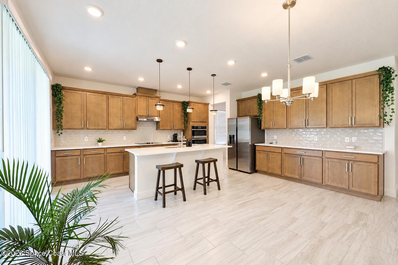 Bright kitchen with warm wood cabinets, a white island, stainless appliances, and two bar stools.