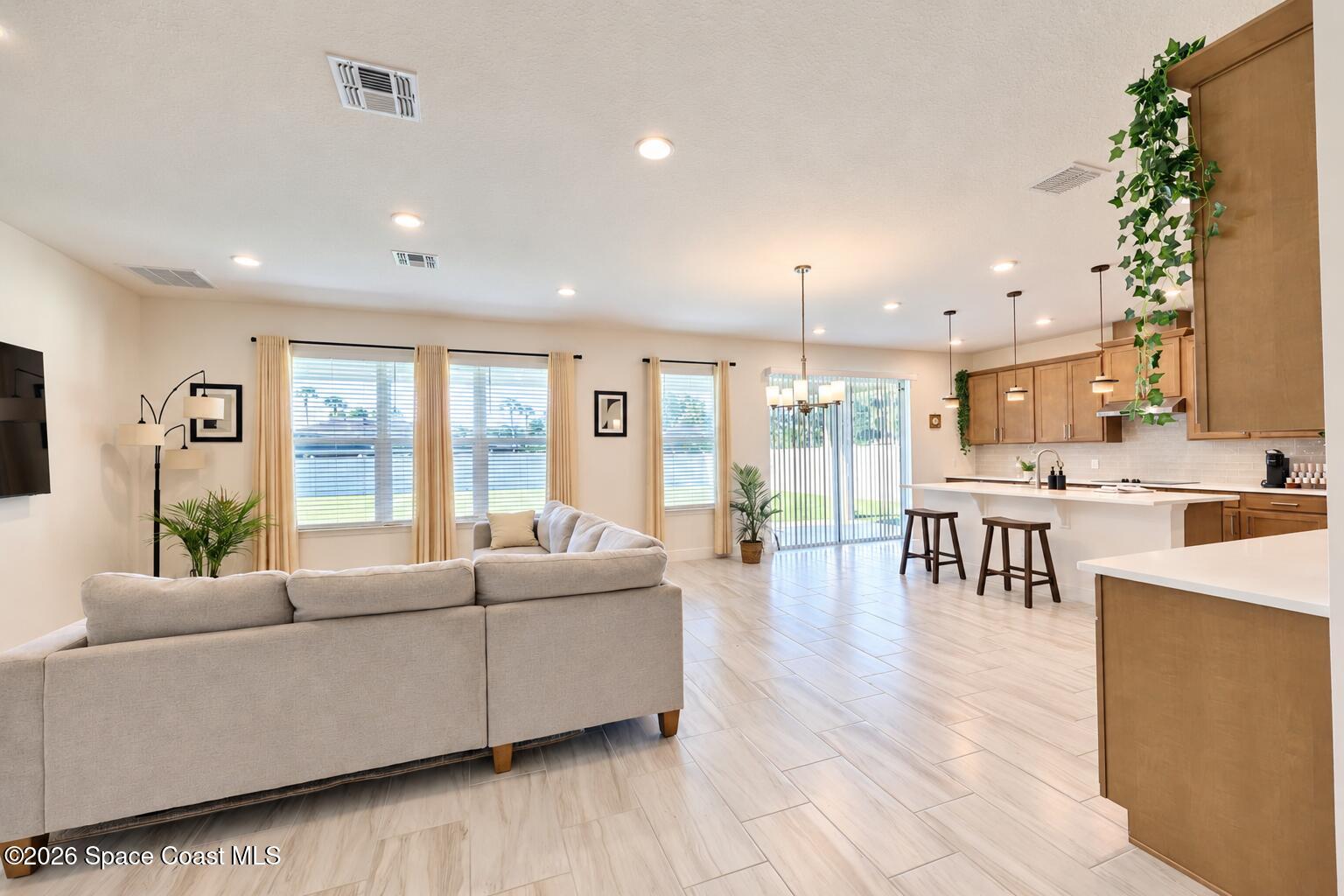 Open-plan living room and kitchen with a light sectional, wood cabinetry, and island seating.