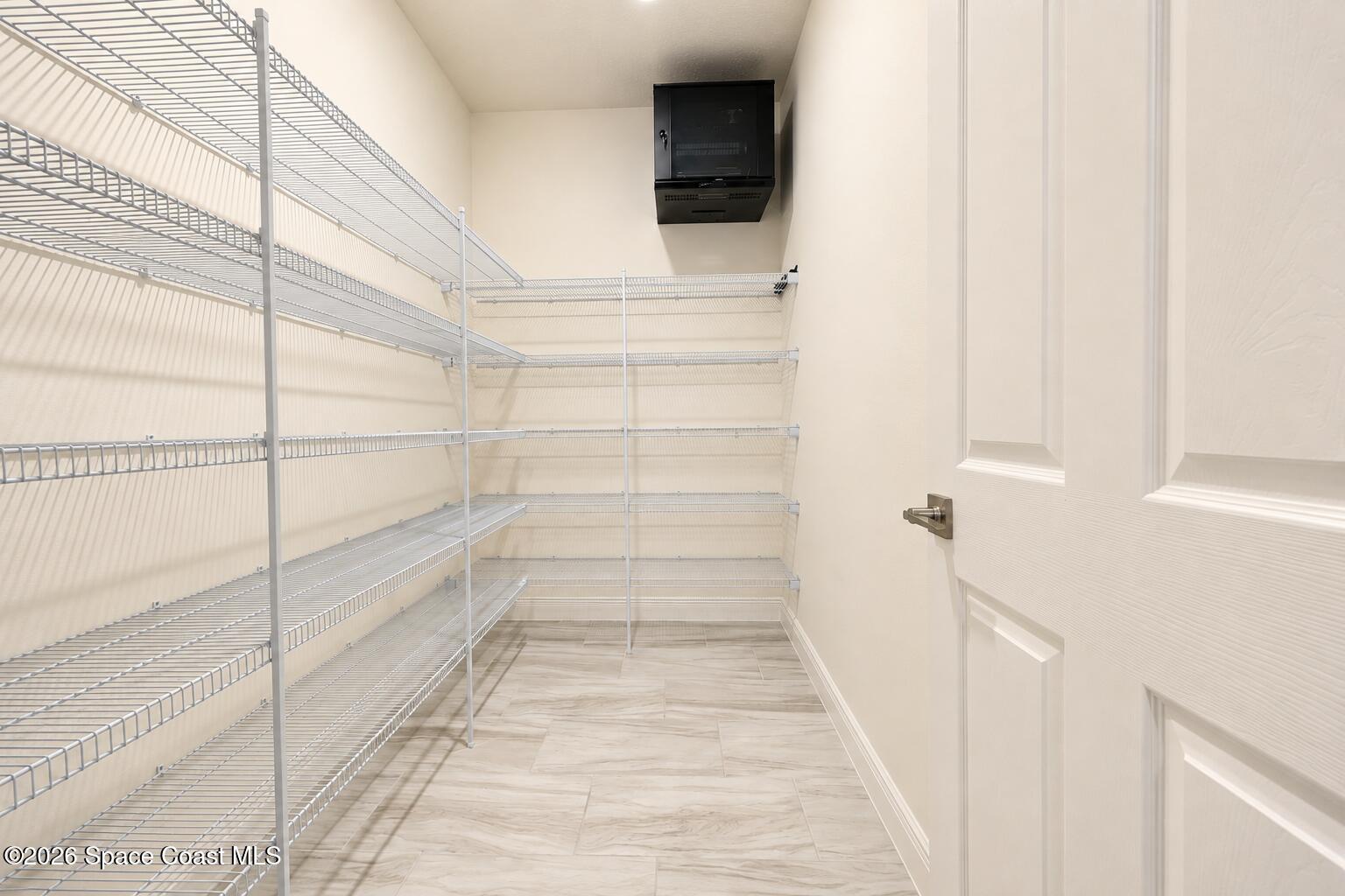Walk-in closet with extensive white wire shelving and light tile flooring.