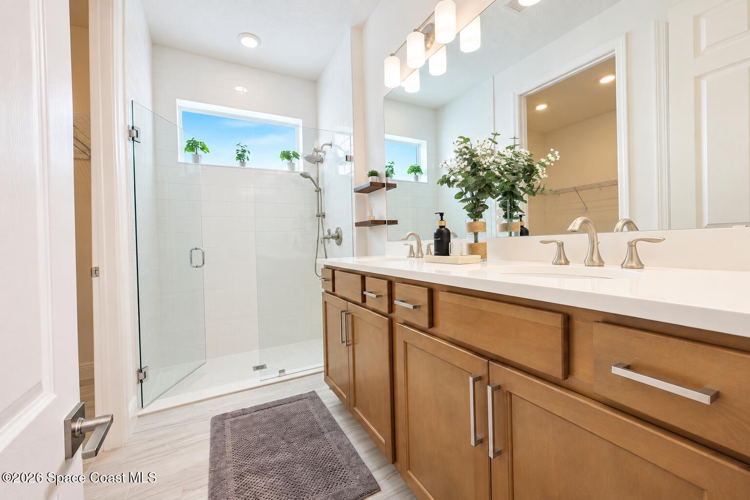 Bathroom with a glass walk-in shower and wood double-sink vanity.