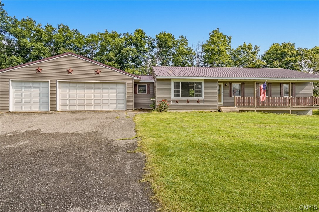 Single-story tan home with a two-car garage, covered porch, and broad front lawn.